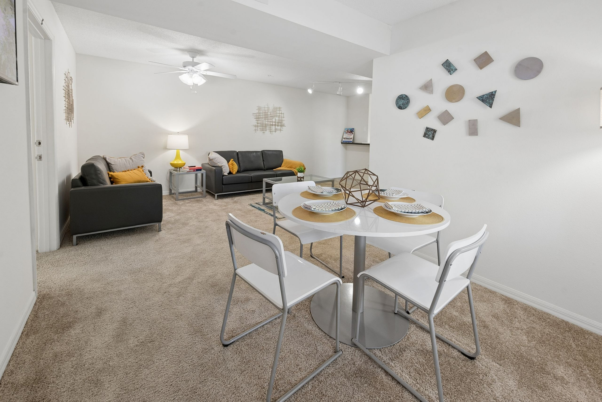 Inviting living space with modern decor, featuring two sleek sofas, a contemporary dining area, and chic geometric wall art.