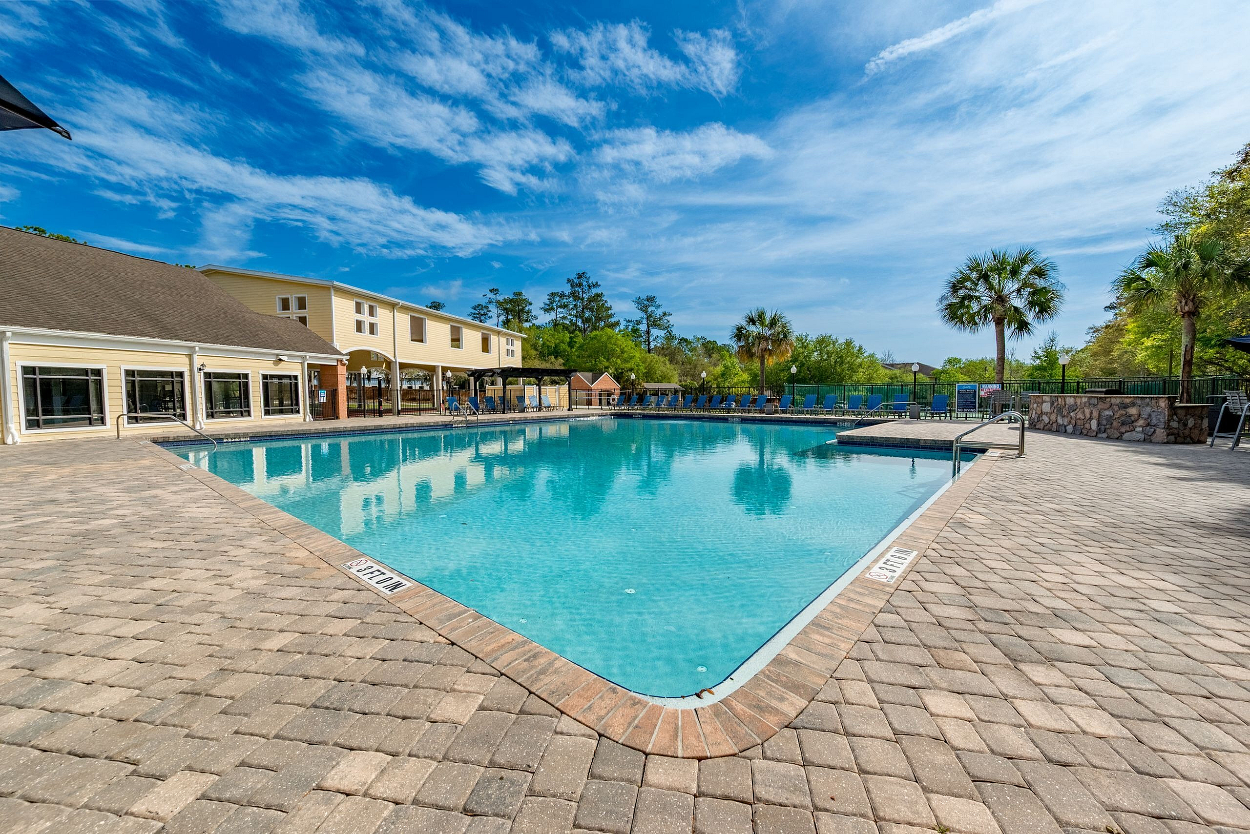 Luxurious outdoor pool area with pristine waters, surrounded by palm trees and modern amenities, perfect for relaxation and leisure.