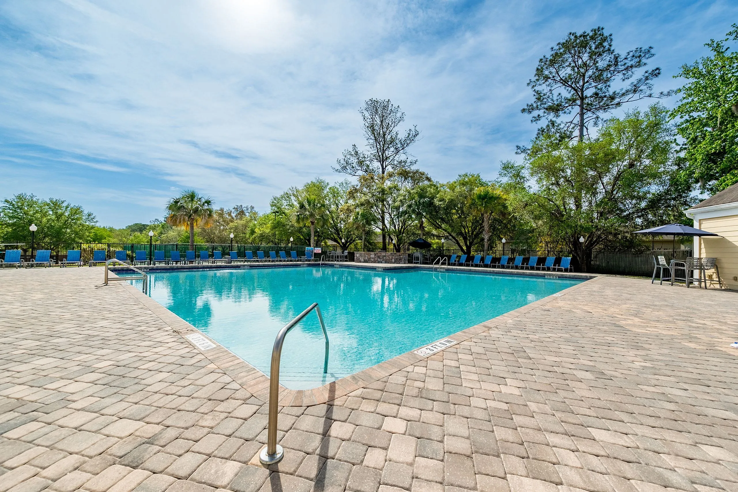 Inviting outdoor pool surrounded by lush greenery and sun loungers, perfect for relaxation and leisure.