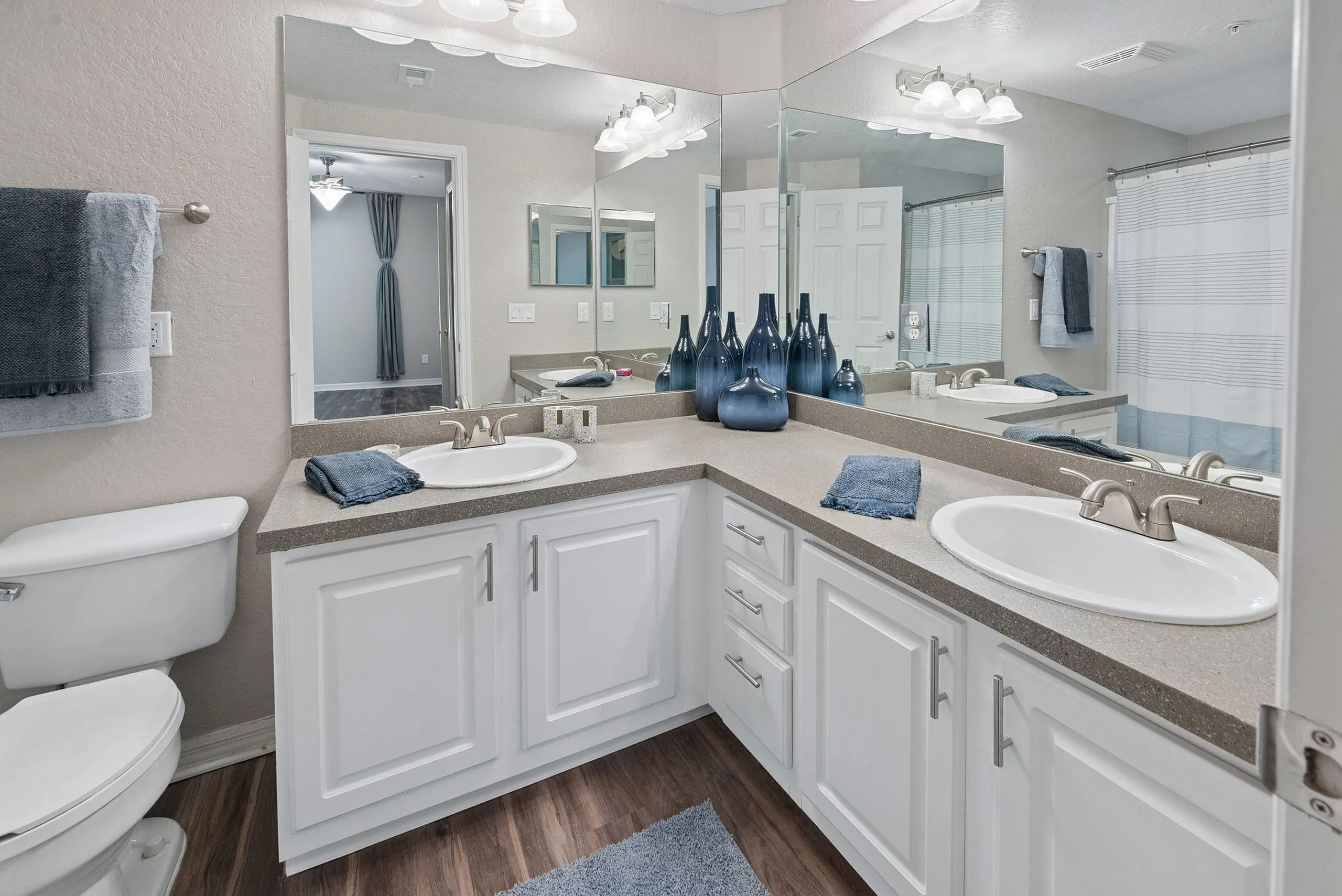 Elegant bathroom featuring a dual-sink vanity, stylish decor, and modern lighting with a glimpse into a chic adjacent room.