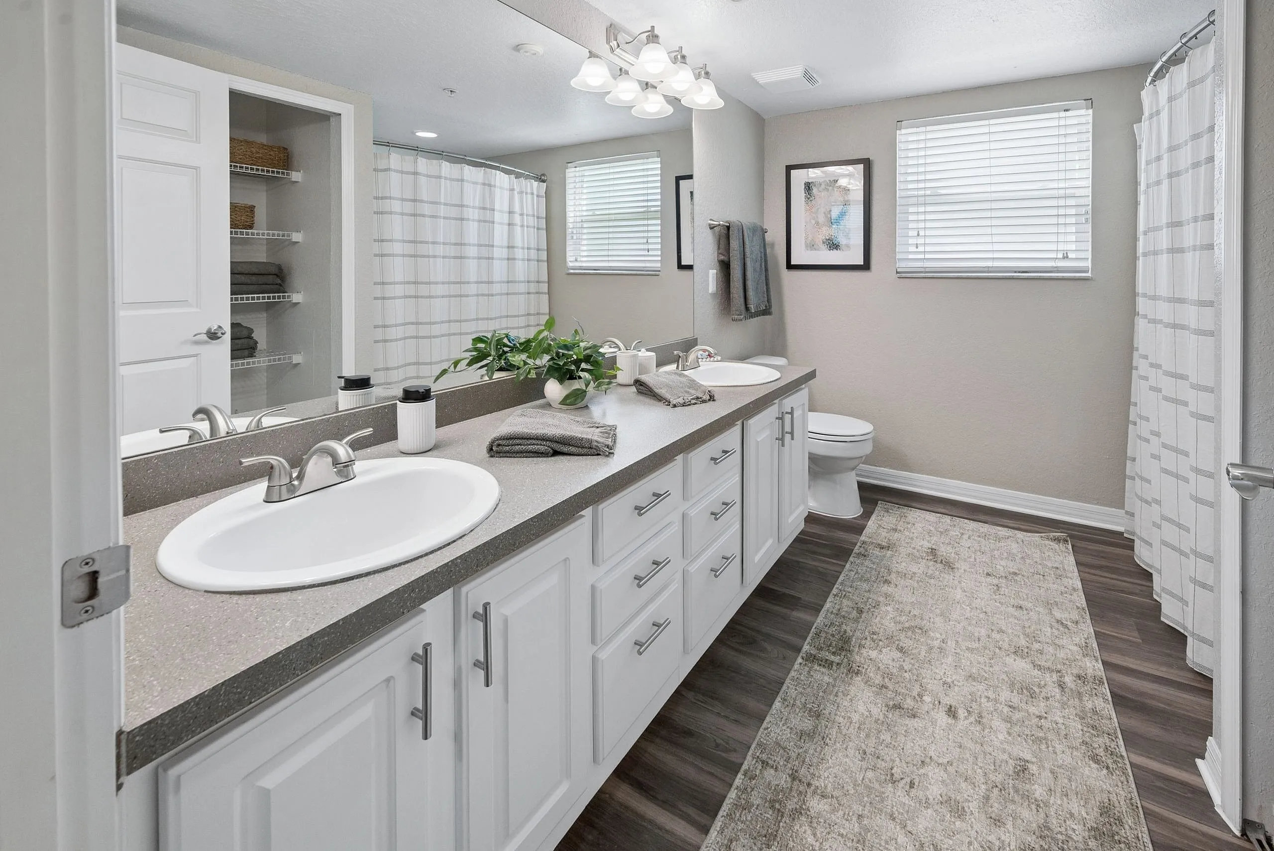 Elegant bathroom featuring dual sinks, modern fixtures, and chic decor with ample storage and warm lighting.