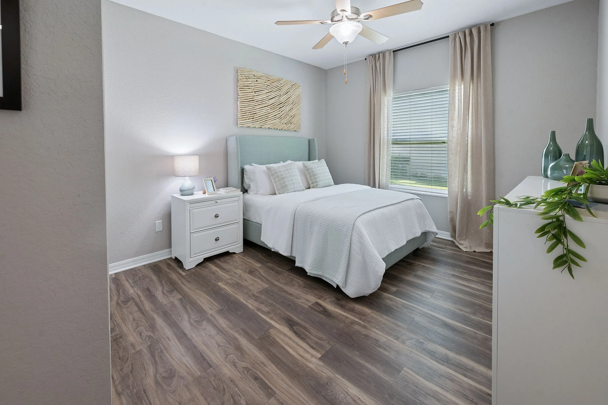 Charming bedroom with elegant decor featuring a cozy bed, modern nightstand, and natural light through large windows, perfect for relaxation.