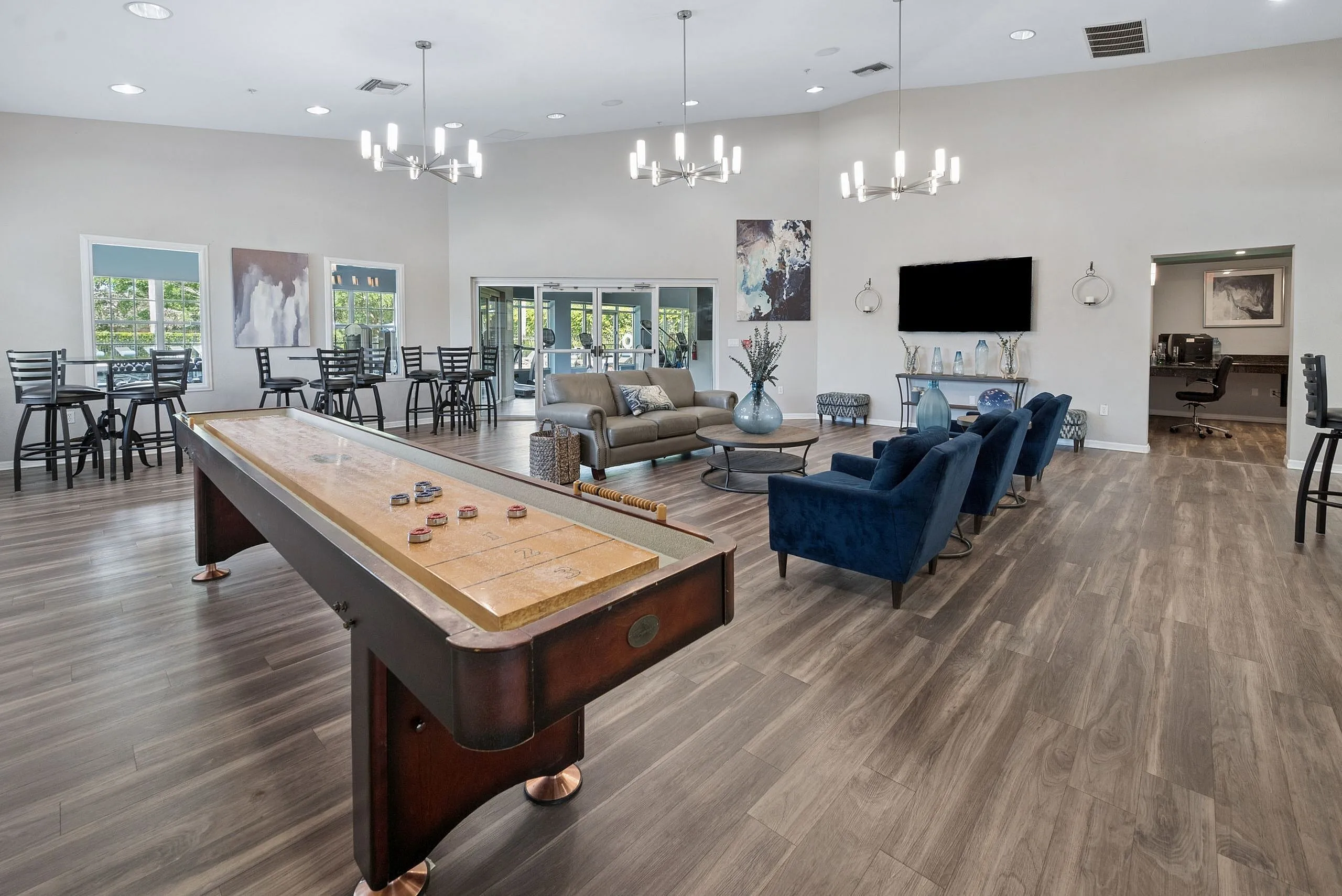 Luxurious communal lounge featuring stylish seating, chic decor, and a classic shuffleboard table, ideal for social gatherings.