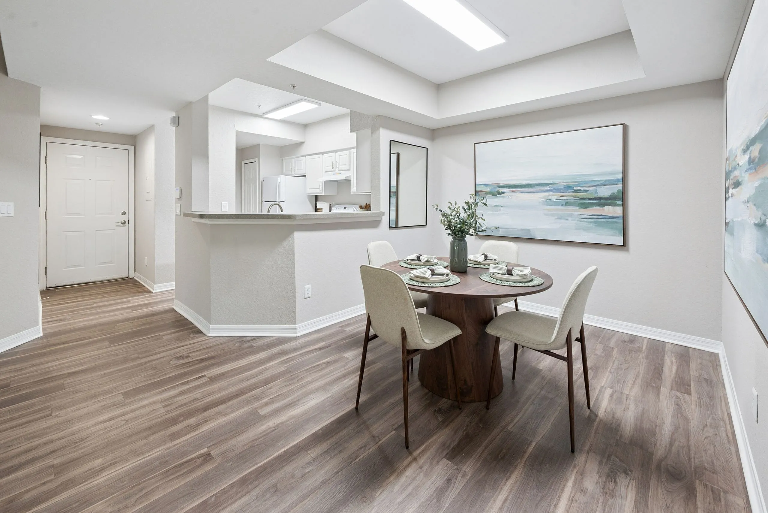 Elegant dining area with modern decor, featuring a round table set for four and a stylish open kitchen layout with sleek flooring.