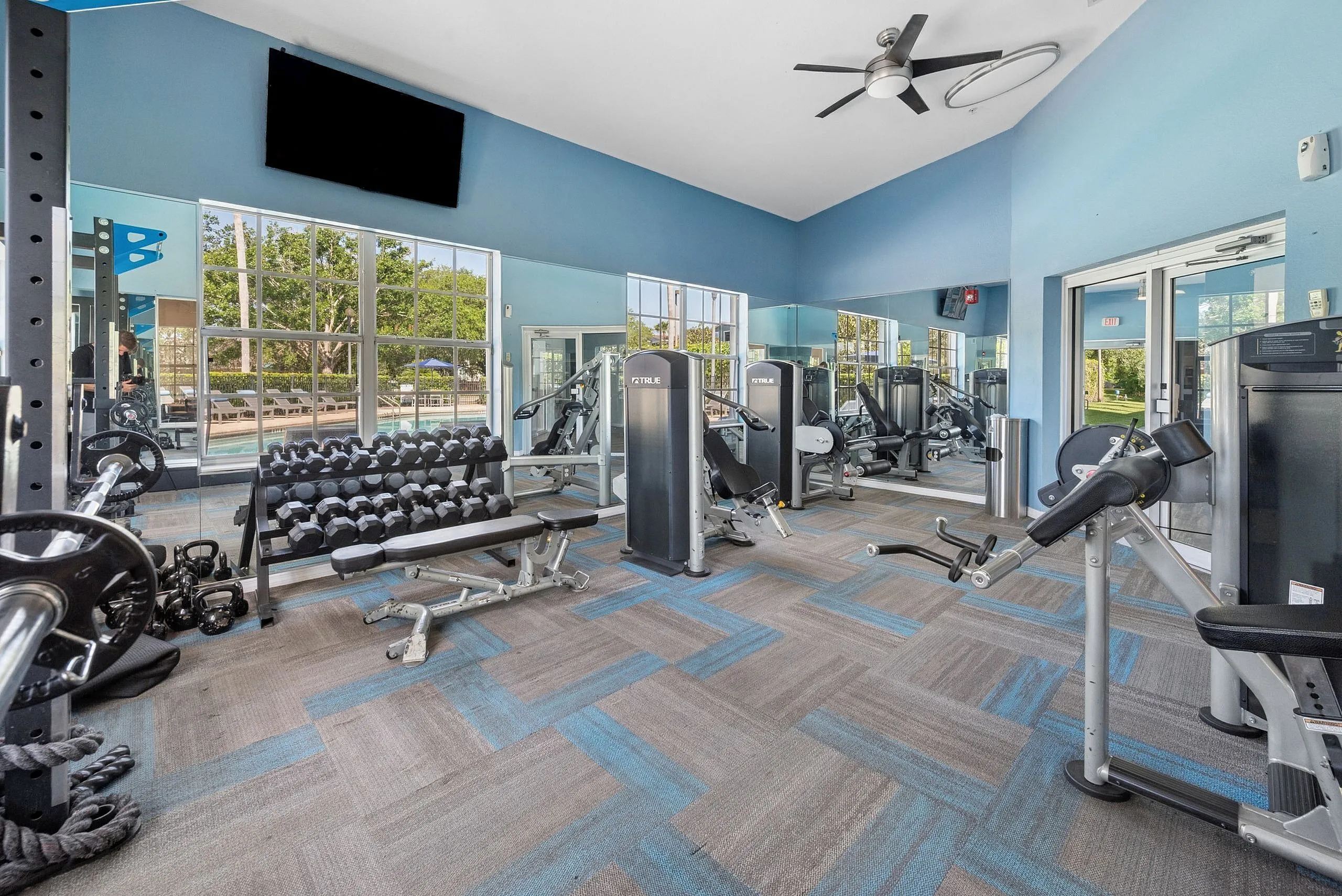 Modern fitness center with state-of-the-art equipment, ample natural light, and a mirrored wall for an invigorating workout experience.