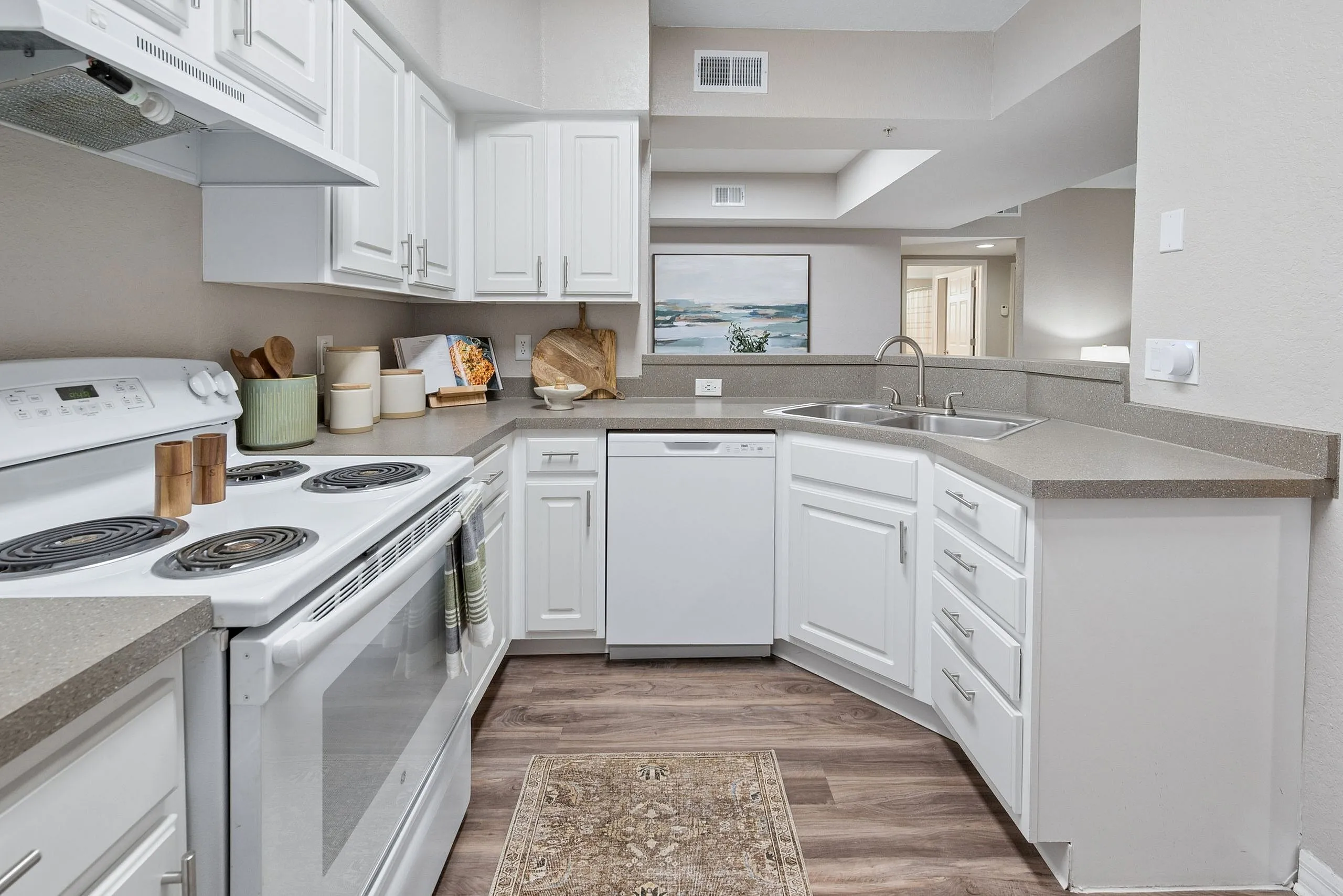 Bright modern kitchen with sleek white cabinetry, stainless steel appliances, and warm wood flooring, perfect for culinary enthusiasts.