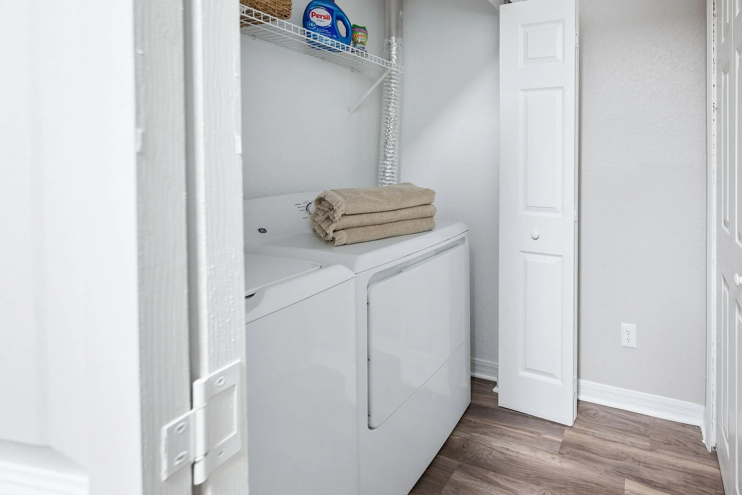 Modern laundry nook with sleek white washer and dryer, equipped with handy shelving for storage.