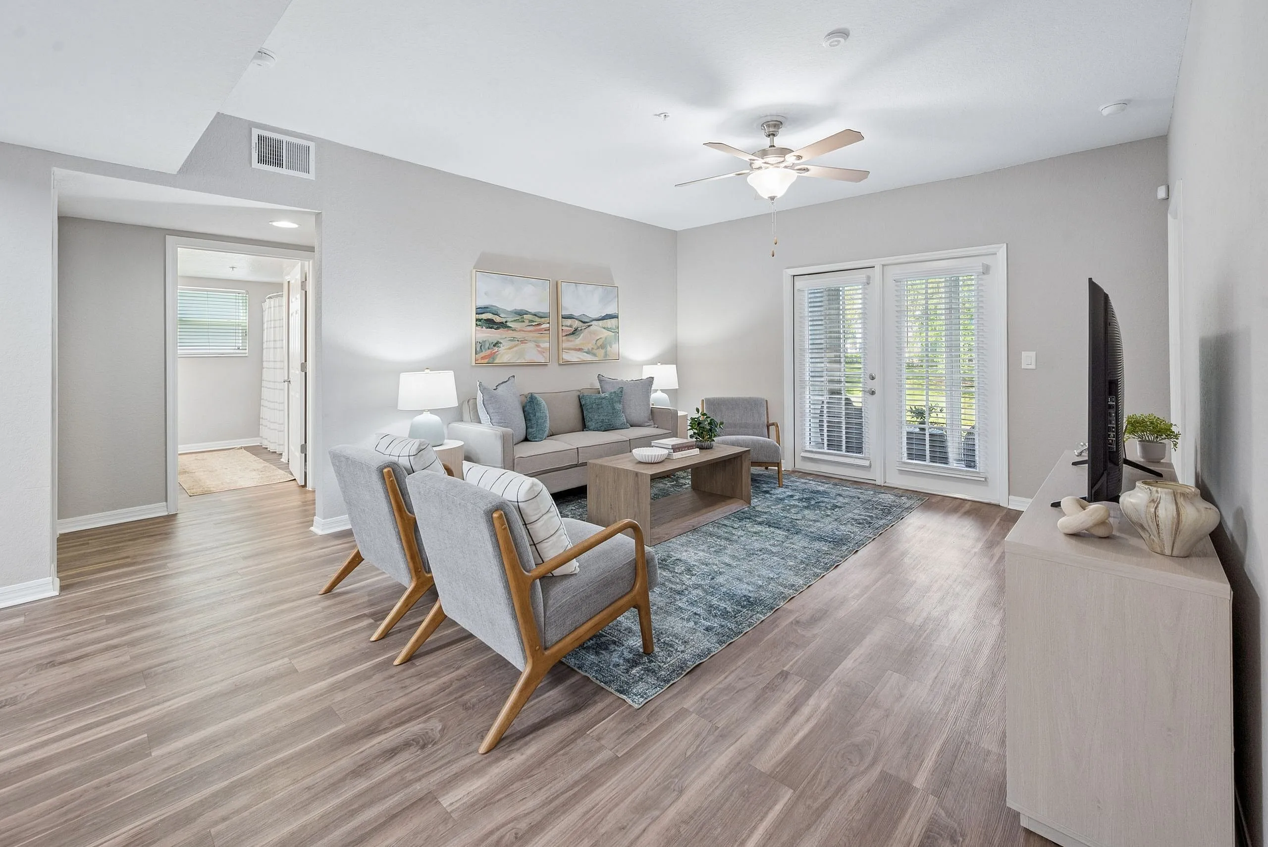 Bright and inviting living room with elegant hardwood floors, modern furniture, and abundant natural light through patio doors.