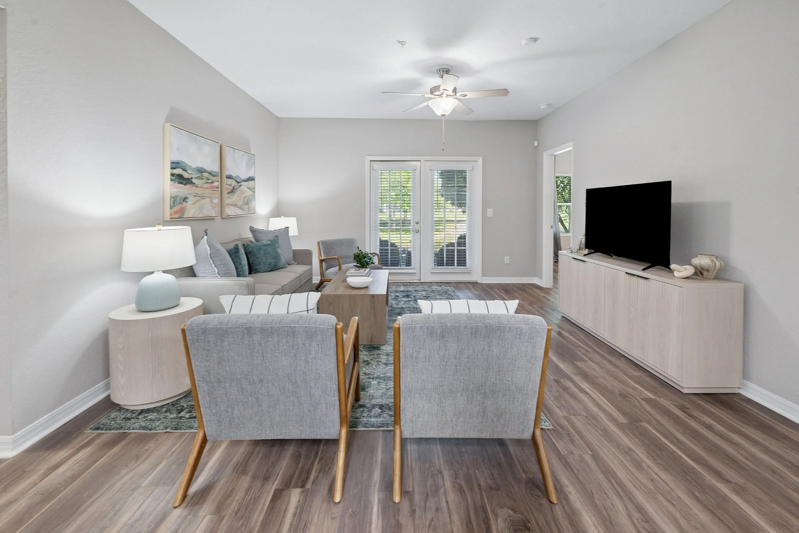 Bright and inviting living room with stylish furnishings, wooden floor, and natural light through French doors.