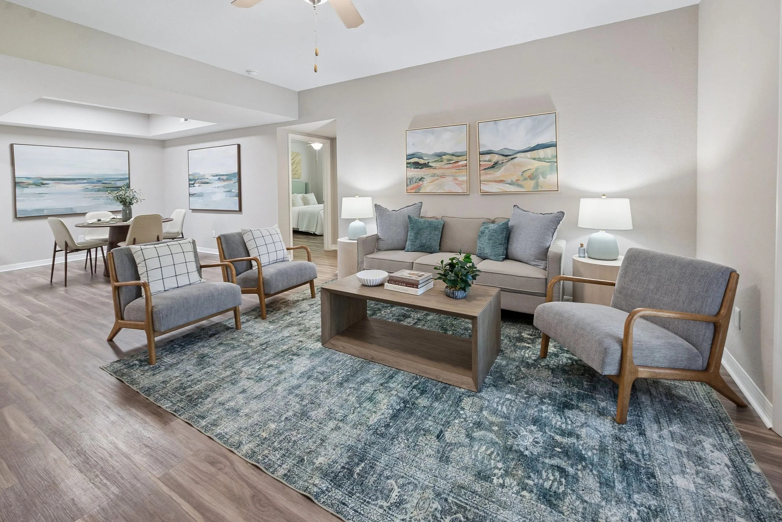 Elegant living room featuring modern furniture, accent chairs, and decorative art pieces, seamlessly connecting to a stylish dining area with contemporary artwork.
