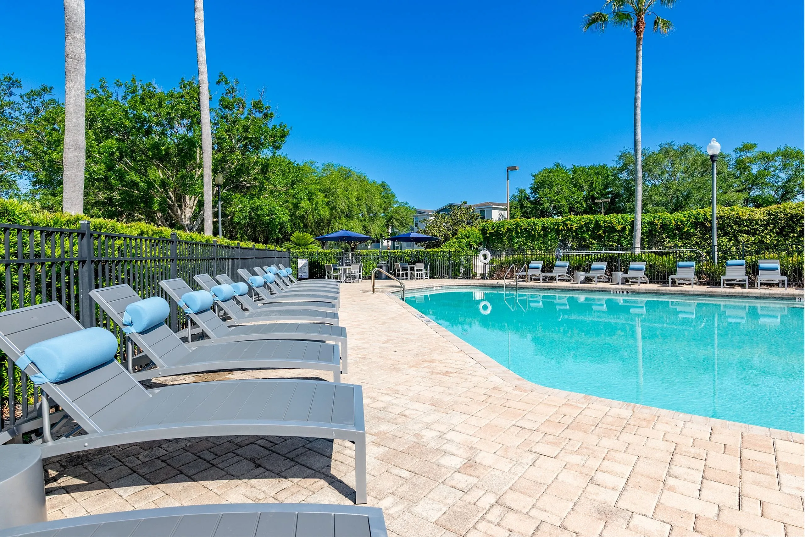 Inviting outdoor pool area with elegant lounge chairs and vibrant greenery, perfect for relaxation and leisure.
