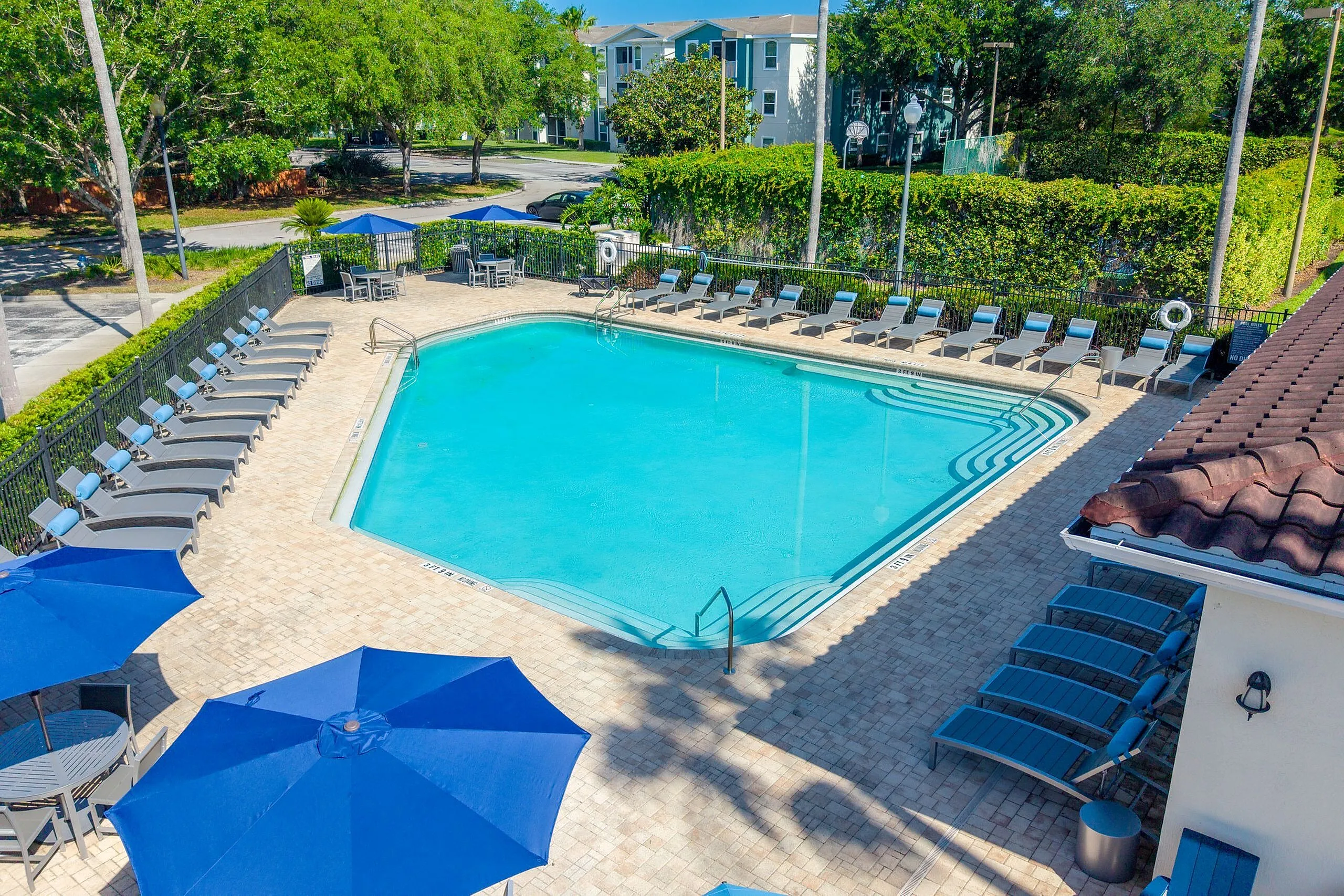 Inviting outdoor pool area with comfortable lounge chairs and stylish blue umbrellas, perfect for relaxation and leisure under the sun.