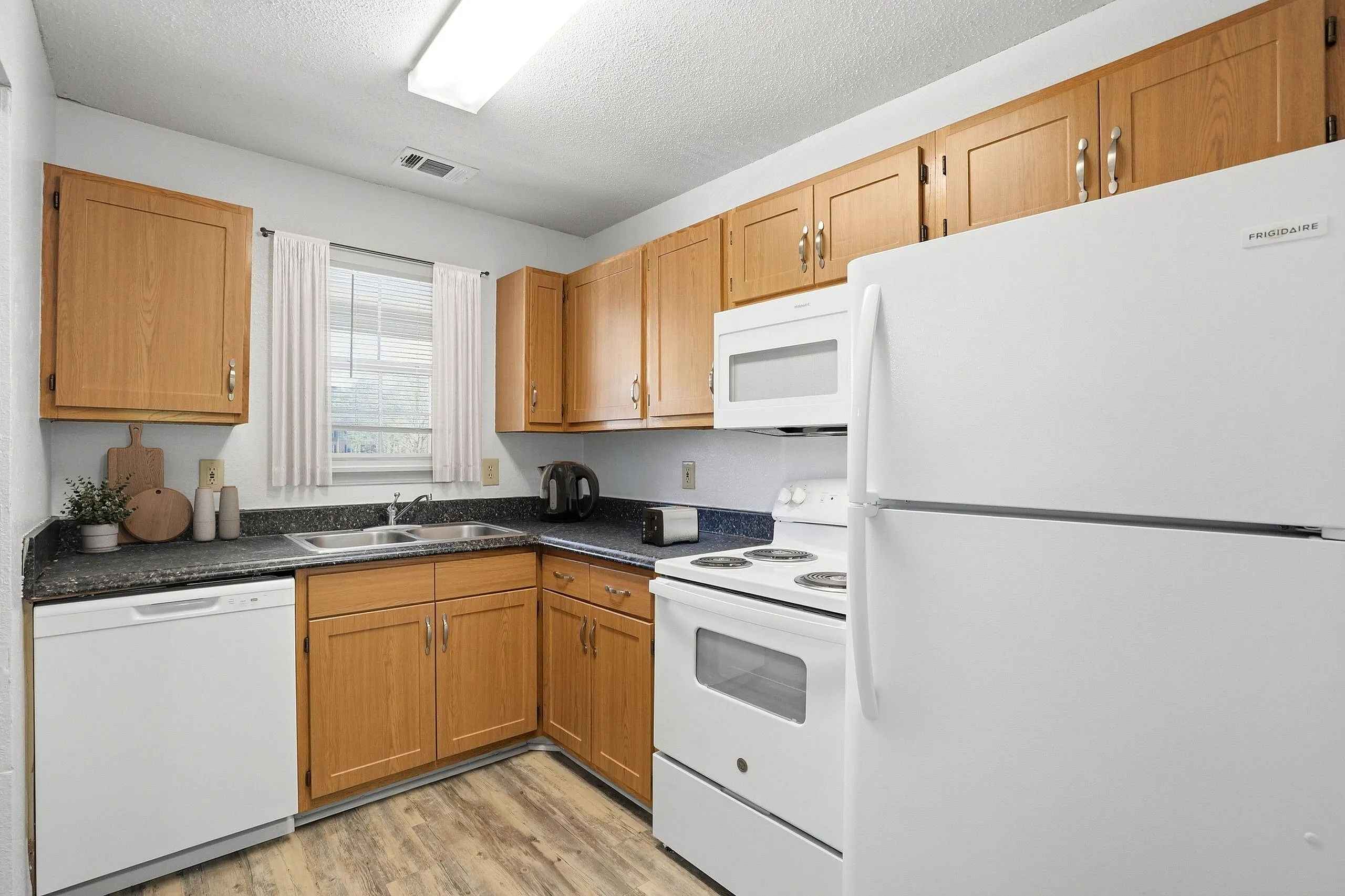 Bright and cozy kitchen featuring modern white appliances, light wood cabinets, and sleek countertops with ample natural light.
