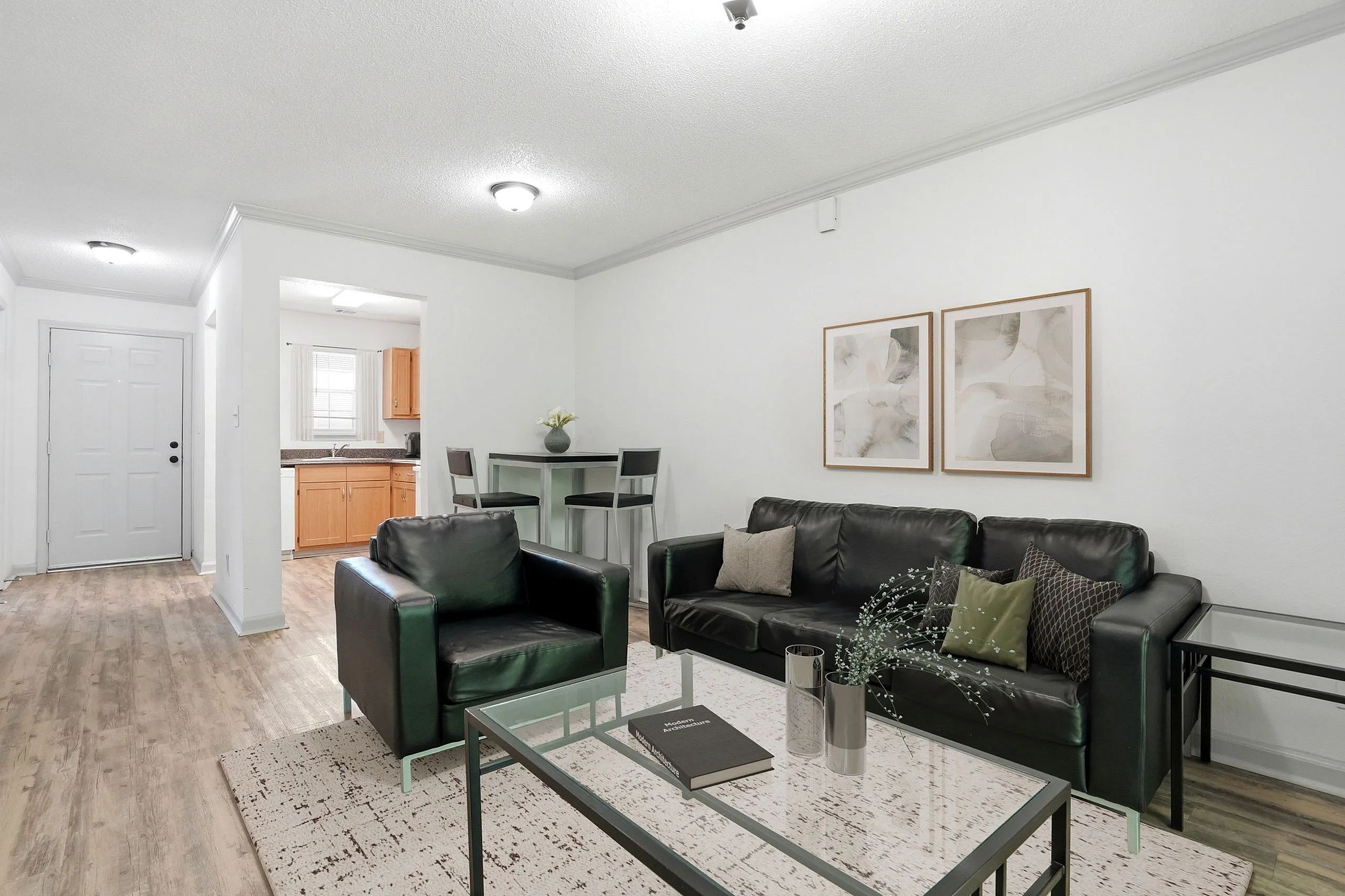 Inviting living room with stylish black leather furniture, modern decor, and open kitchen entry, perfect for cozy living.