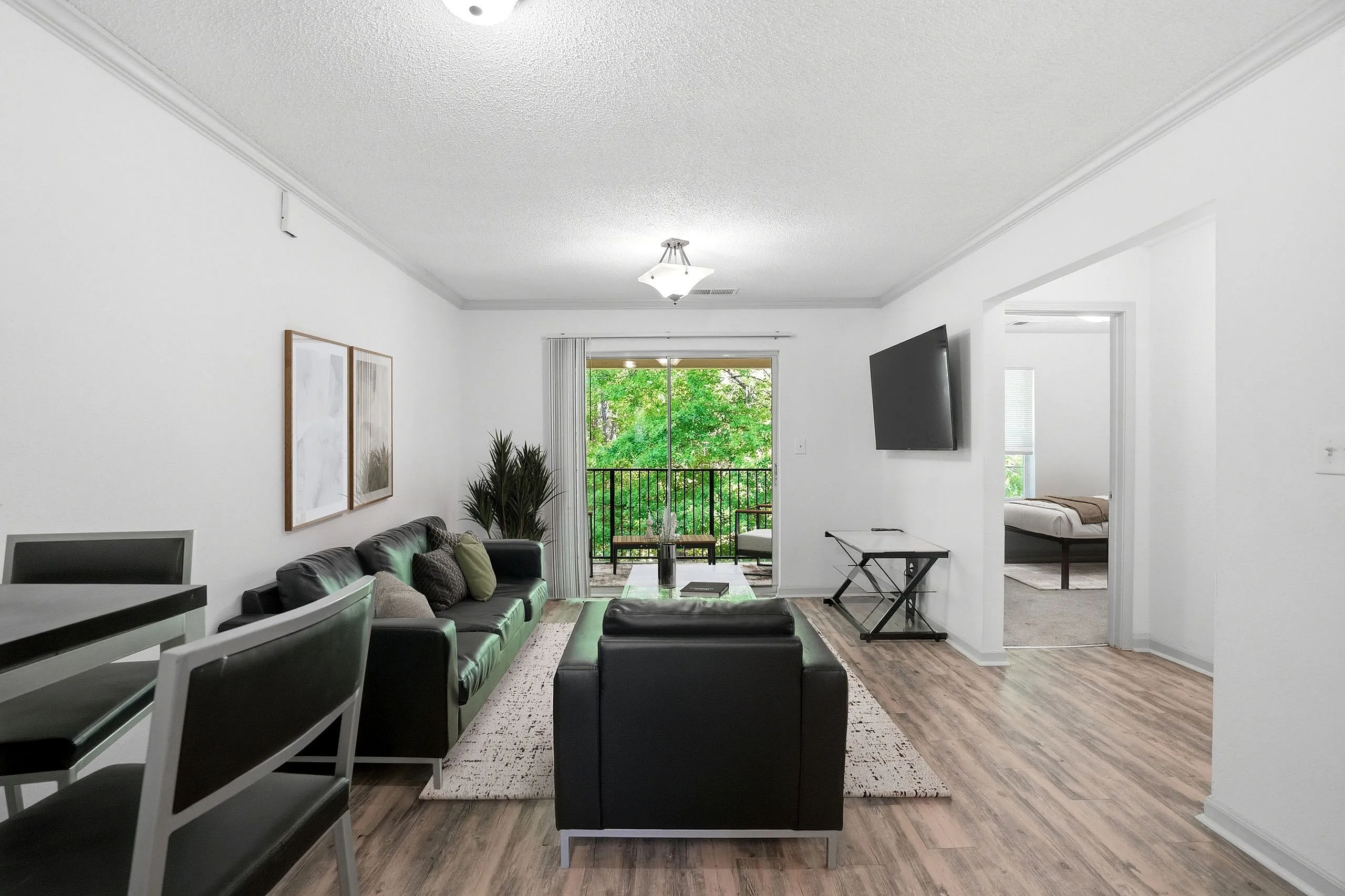 Bright and modern living room with sleek leather furniture, large window with balcony view, and stylish decor.