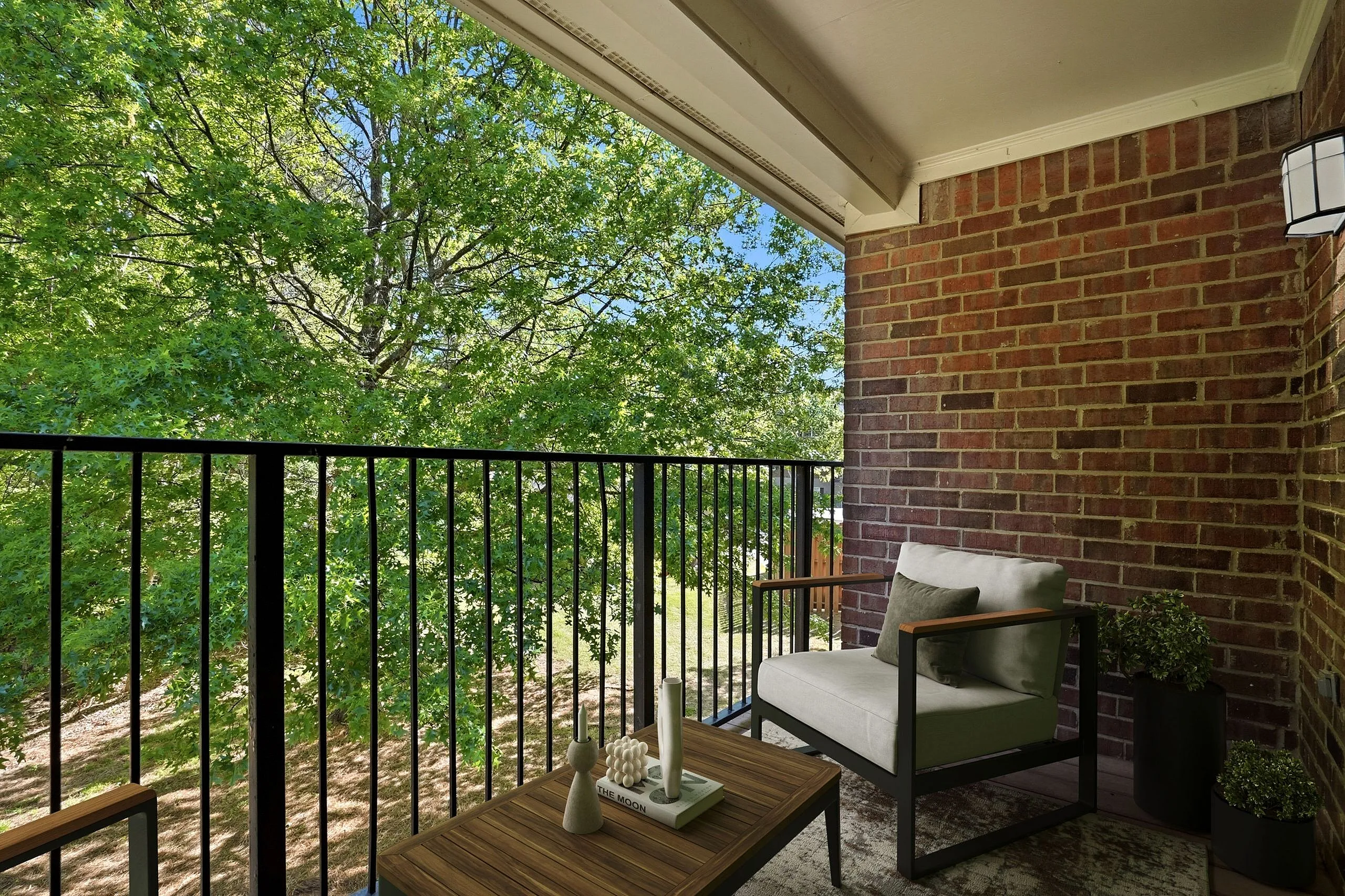 Charming balcony with cozy seating overlooking lush greenery, framed by elegant brick walls.