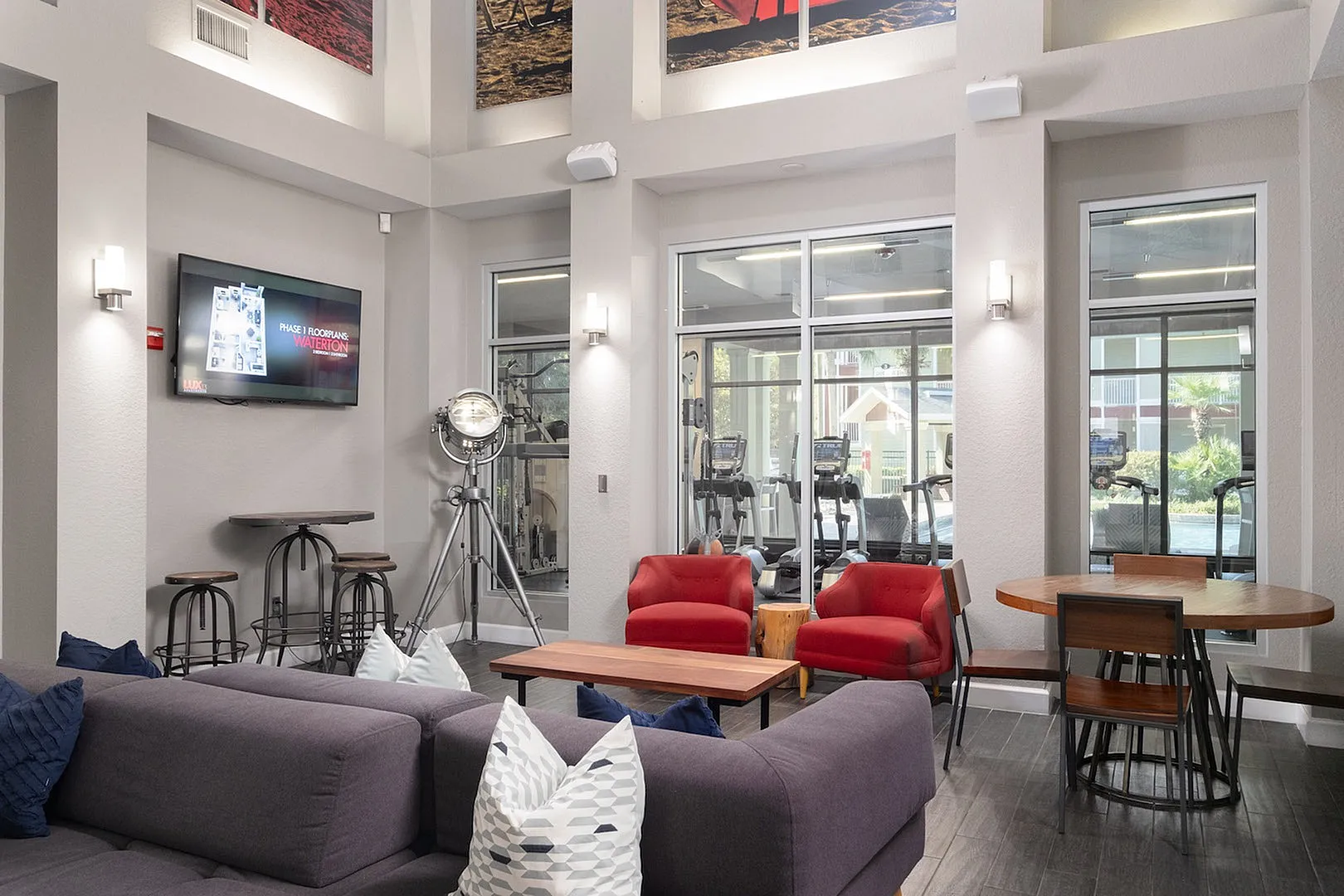 Luxurious and modern lounge area with plush seating, contemporary decor, and a scenic view of the adjacent fitness center through large glass windows.