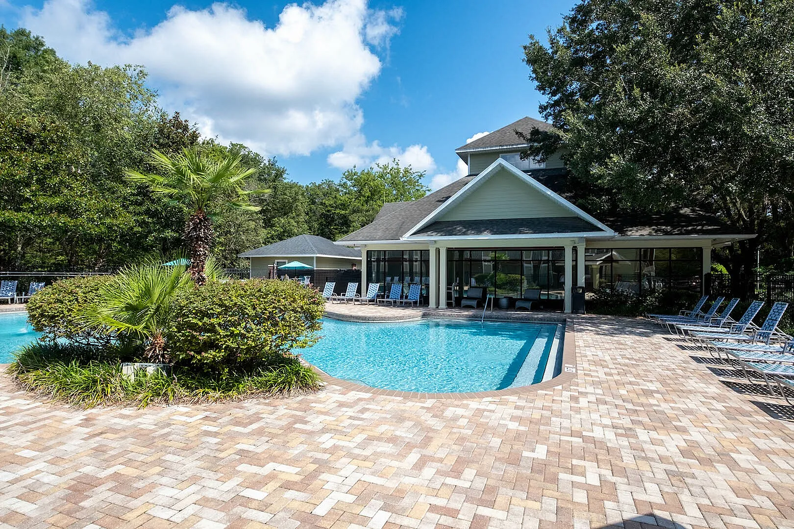 Inviting community pool with sun loungers set amidst lush greenery and modern clubhouse.
