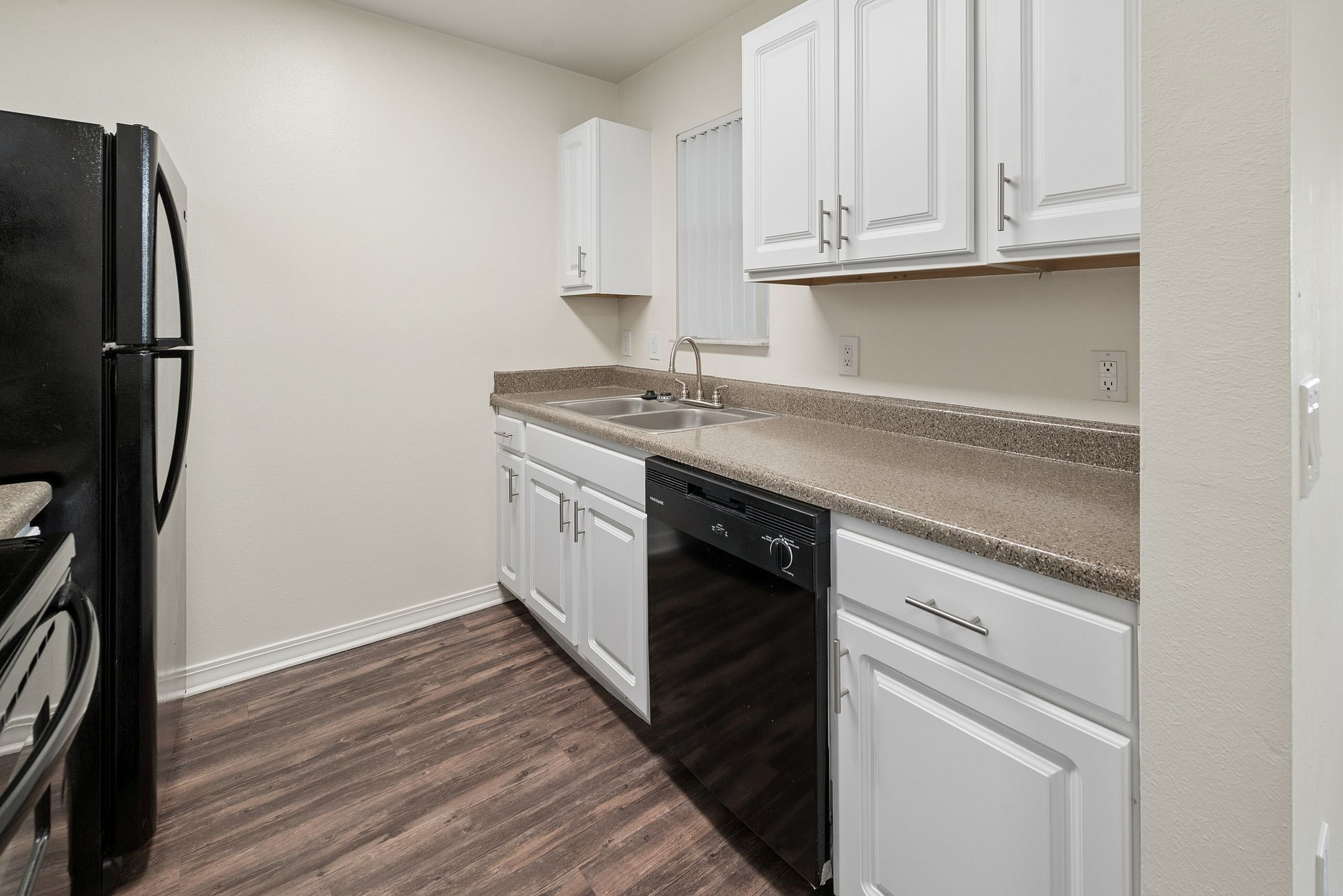 Modern kitchen with sleek white cabinets, elegant granite countertops, and a stylish black appliance set.