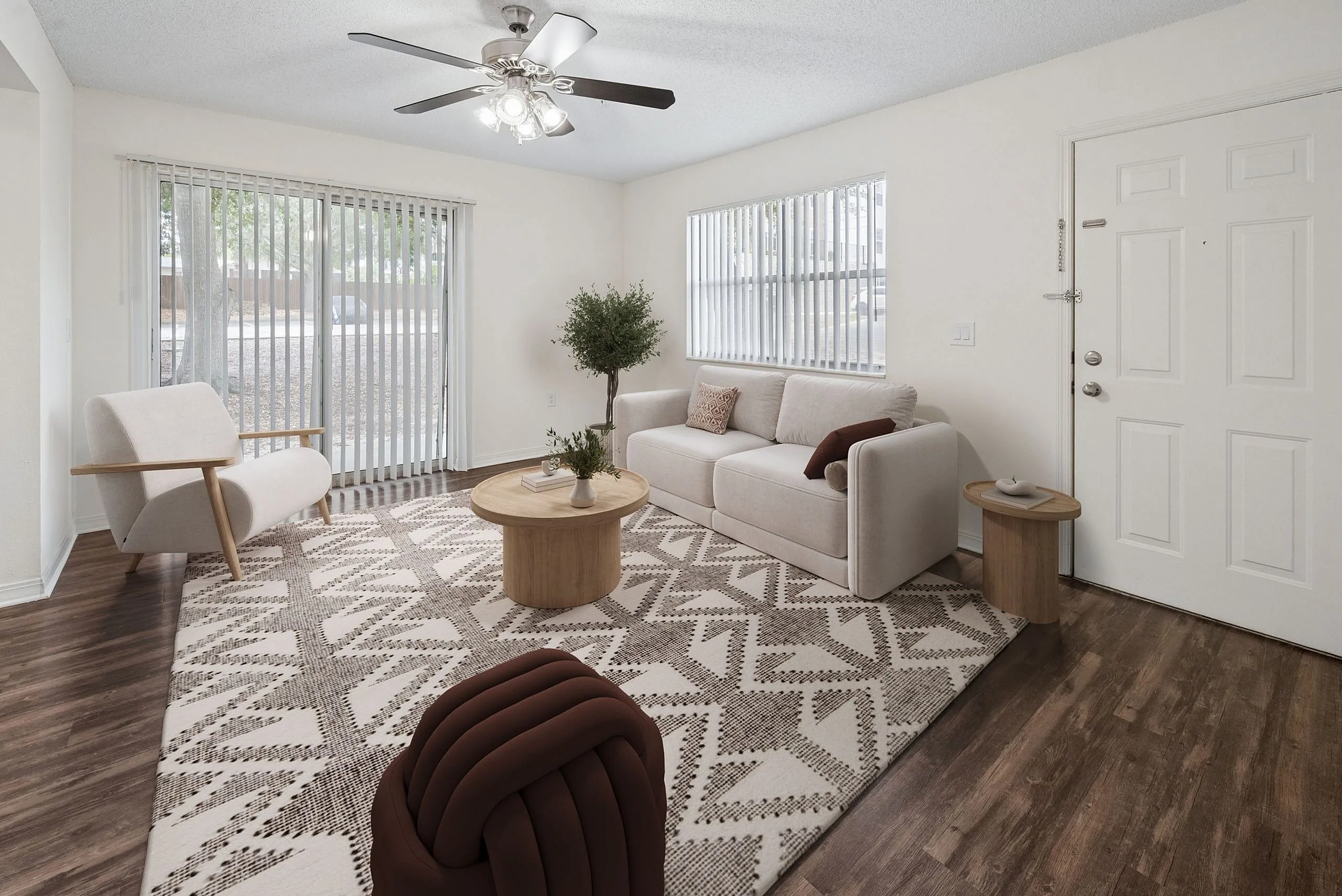 Welcoming living room with modern decor, featuring a plush sofa, stylish armchairs, and a geometric patterned rug on elegant hardwood flooring.