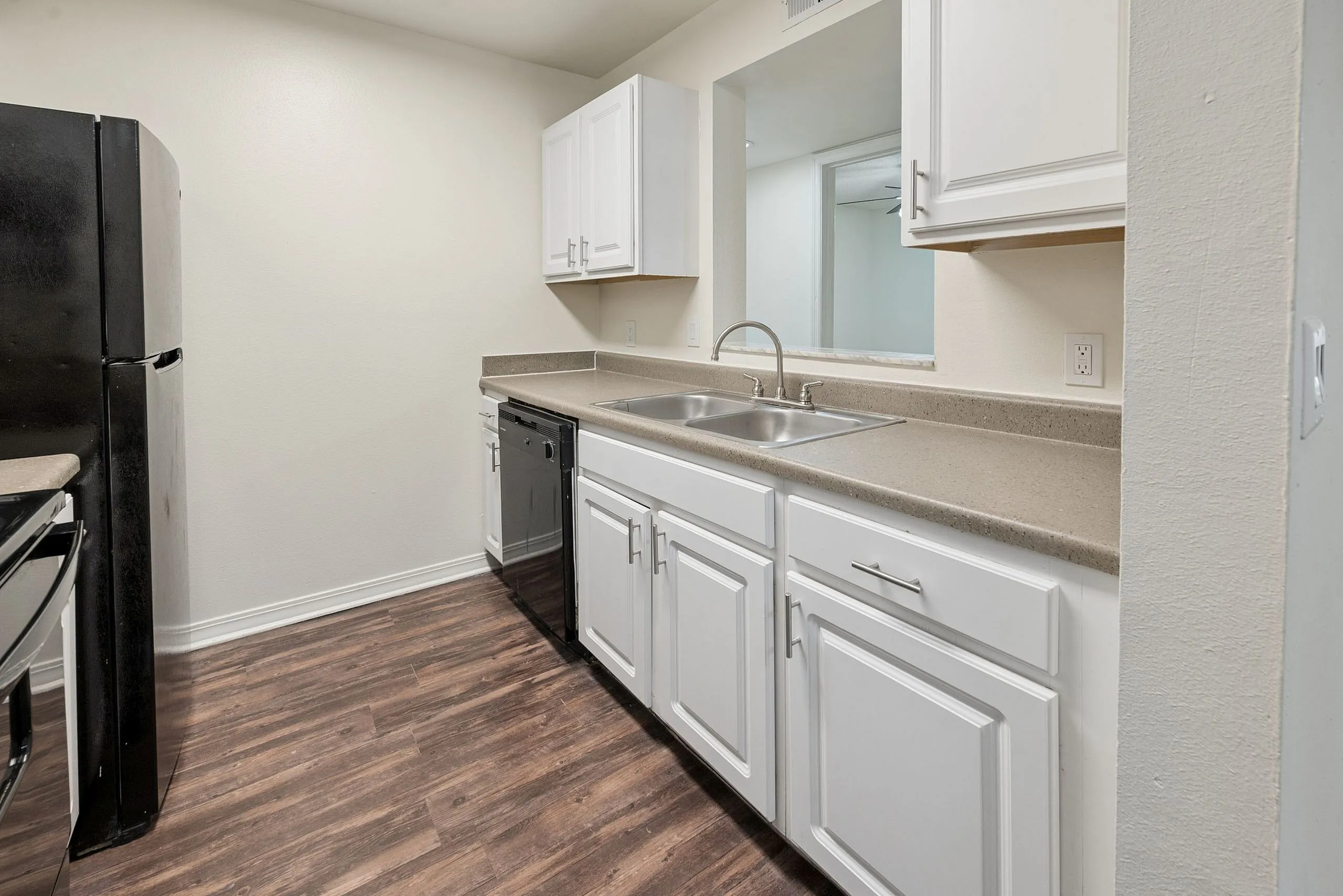 Modern kitchen with sleek white cabinets, stainless steel appliances, and polished countertops, featuring rich wood flooring.