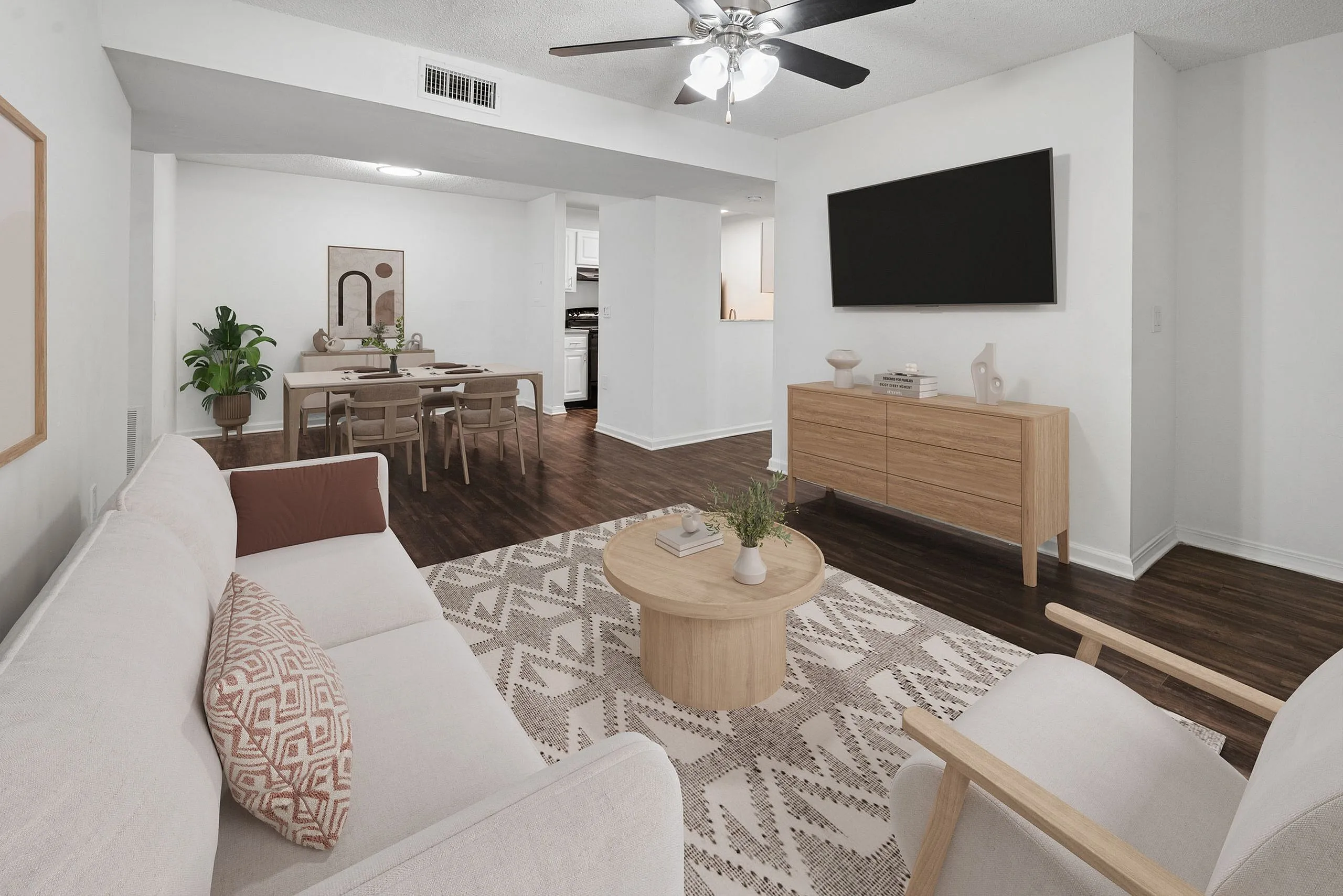 Modern living room with elegant wooden flooring, cozy neutral-toned furniture, and a sleek dining area, creating a welcoming and stylish atmosphere.