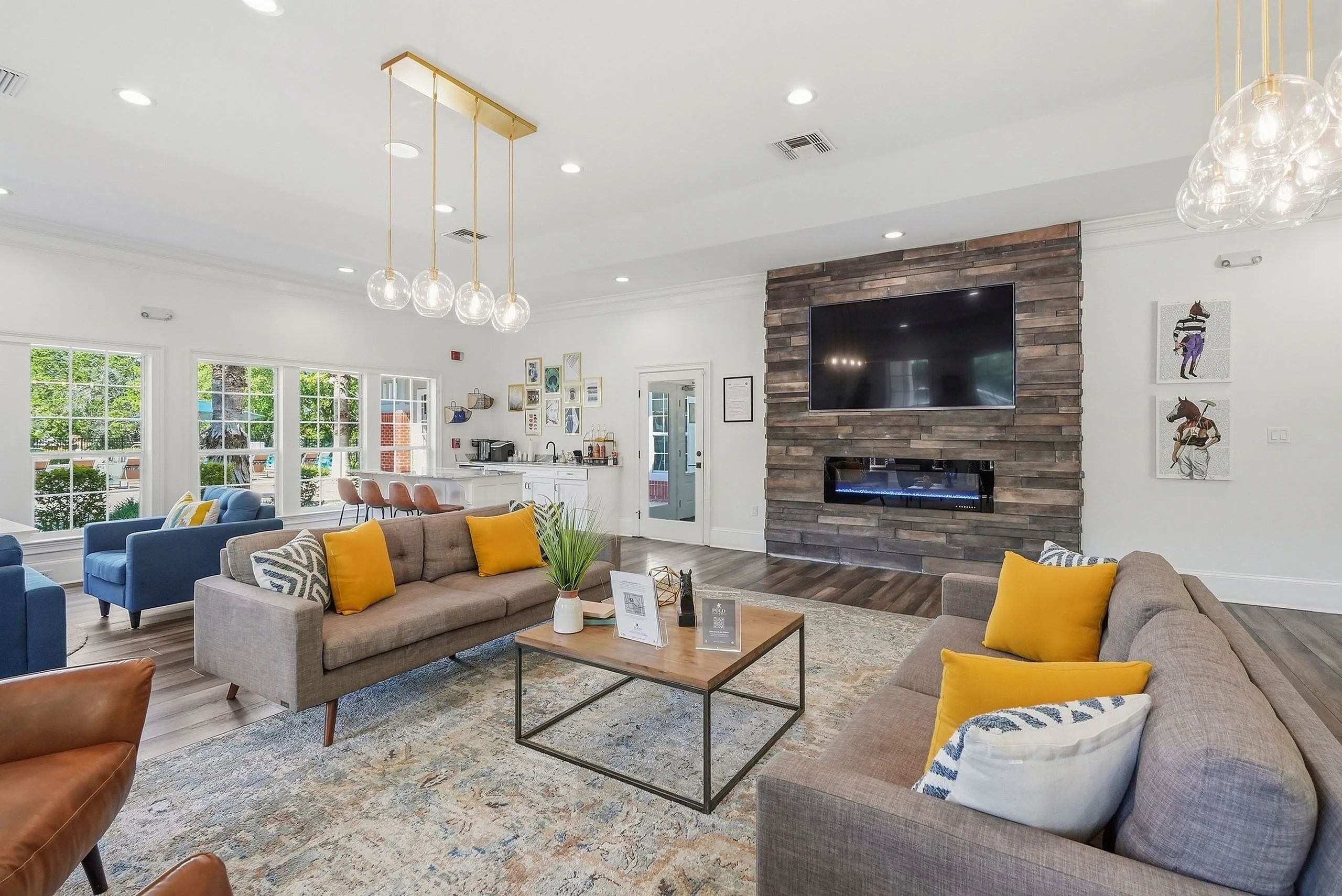 Elegant living area with modern sofas, vibrant yellow accents, a chic stone fireplace, and a large mounted TV, offering a welcoming ambiance and style.