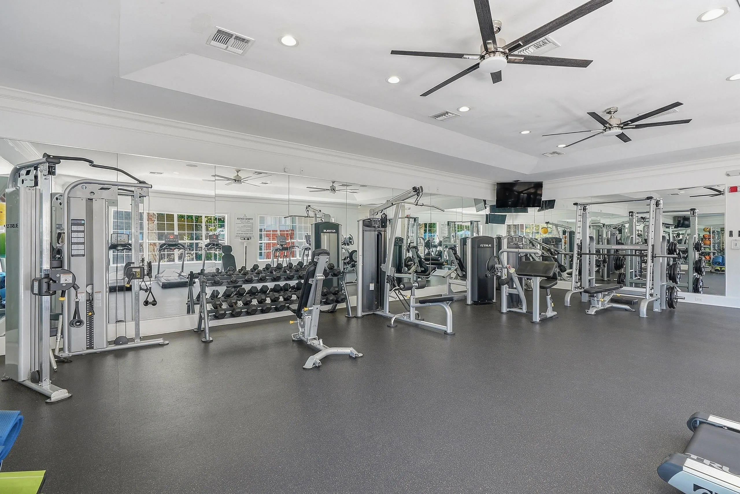 Modern fitness center featuring state-of-the-art weight training equipment, mirrored walls, and ample workout space.