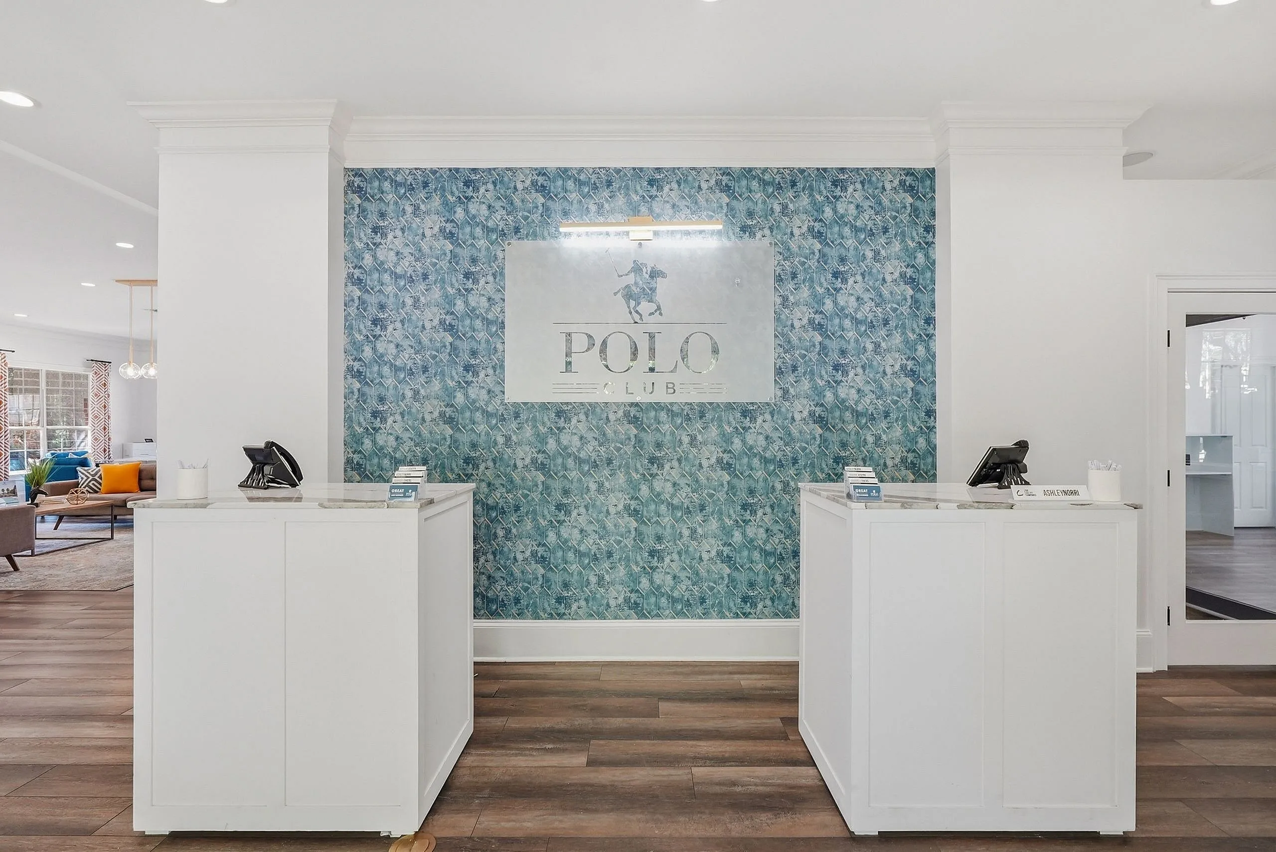 Elegant apartment lobby with a stylish blue patterned accent wall and chic reception desks at Polo Club.