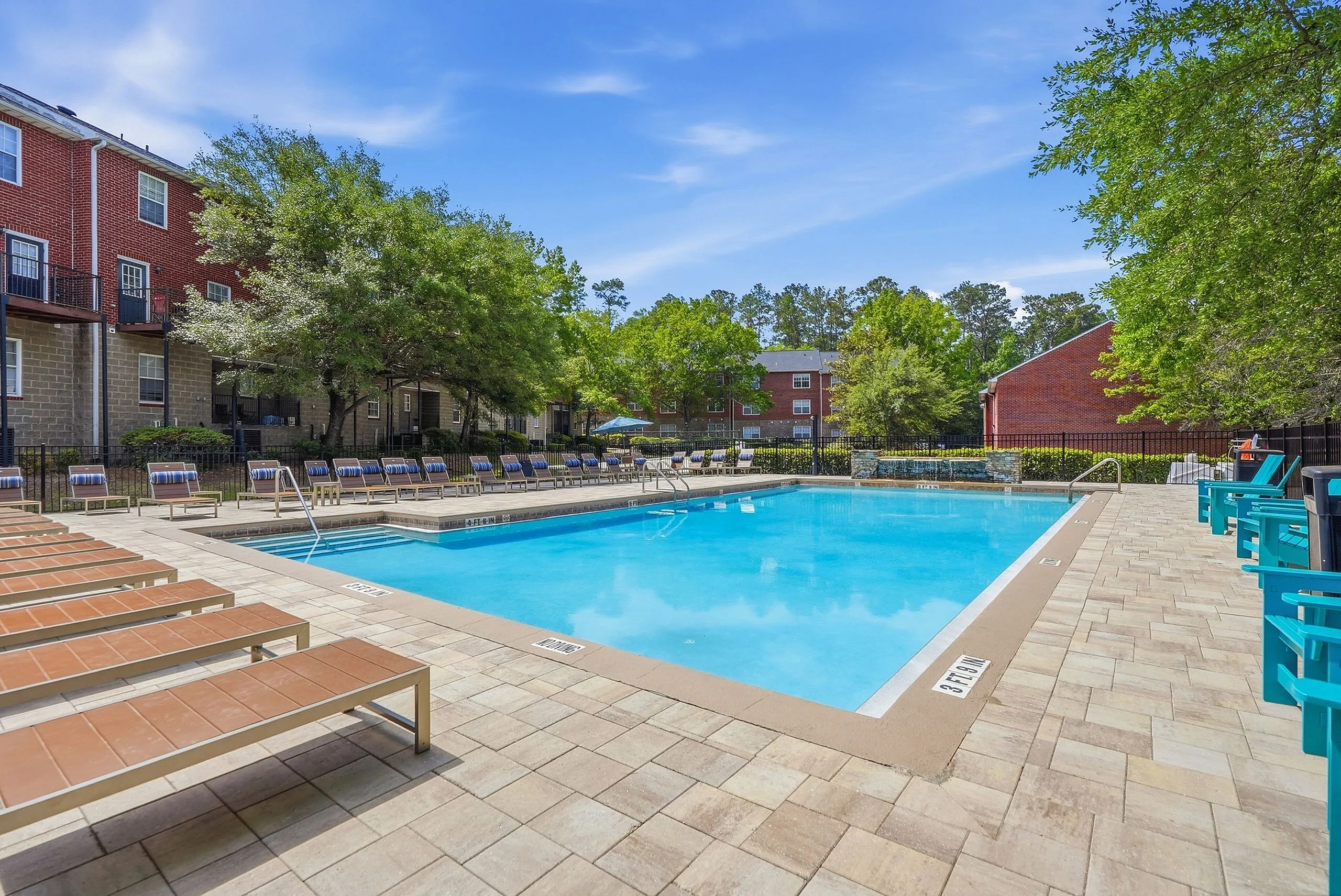 Inviting outdoor pool area surrounded by sun loungers and lush greenery, perfect for relaxation and leisure.