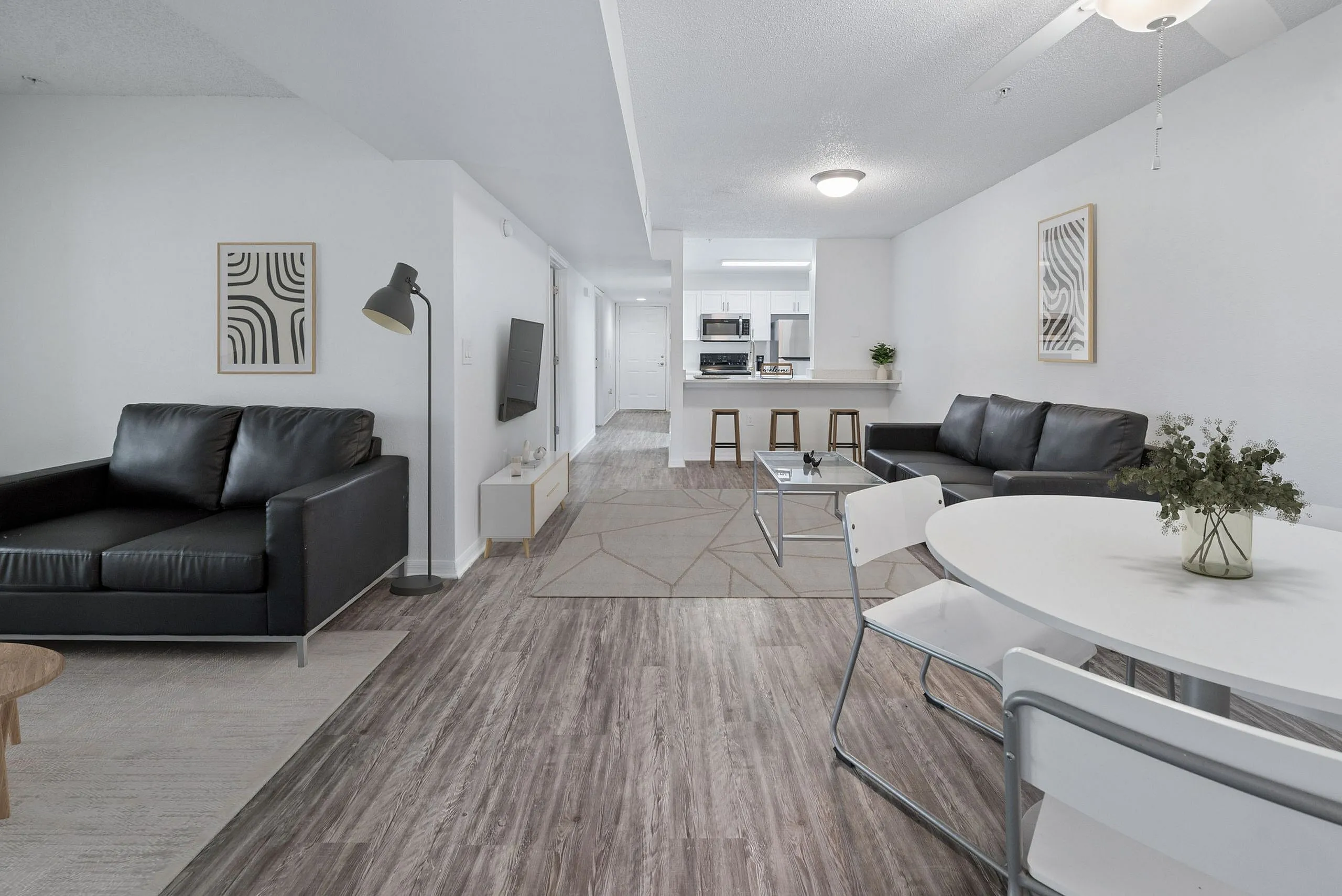 Modern open-concept living space with sleek furnishings, elegant hardwood floors, and a stylish kitchen breakfast bar.