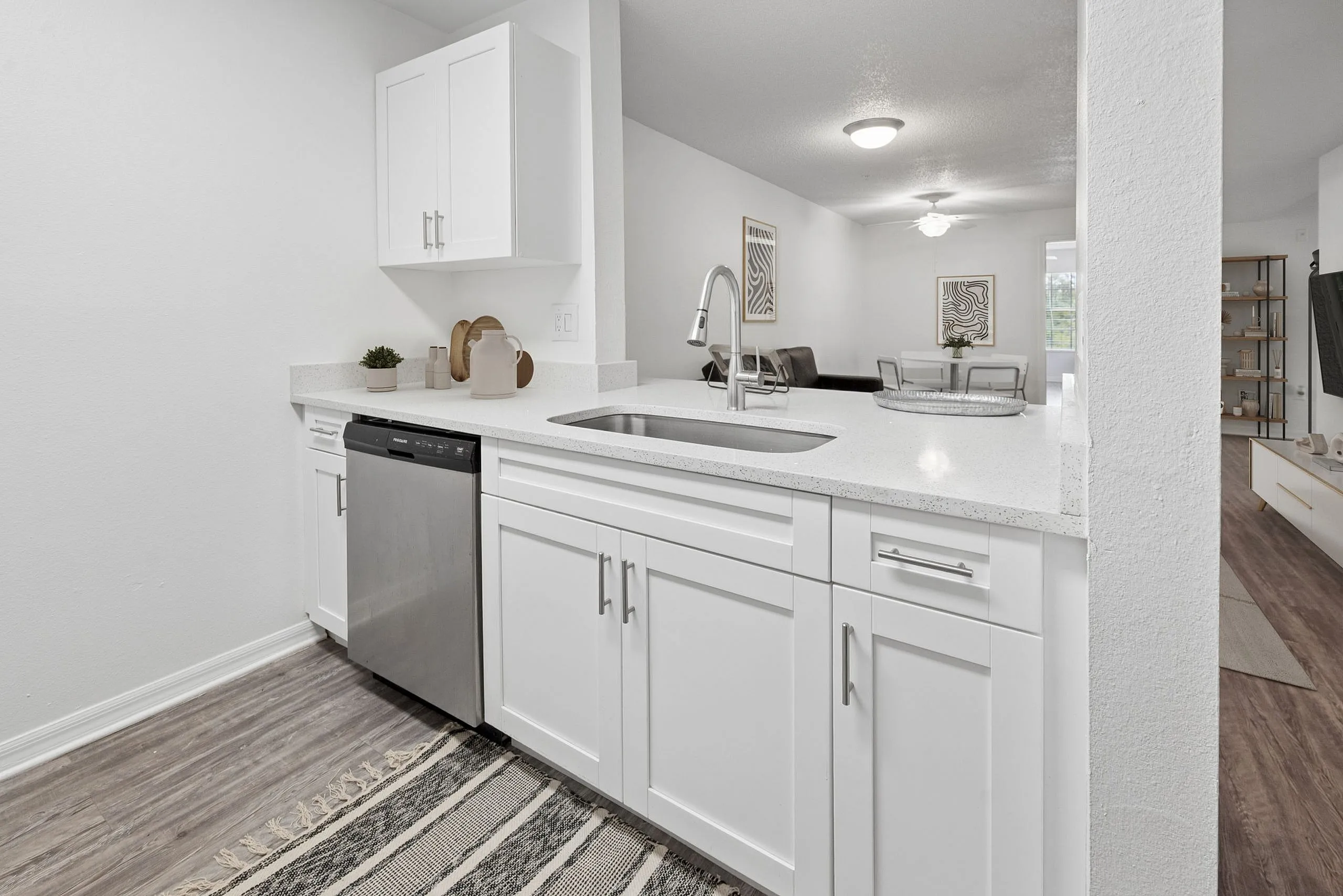 Bright contemporary kitchen with sleek white cabinetry, modern stainless steel appliances, and elegant open-concept design leading to a stylish living area.