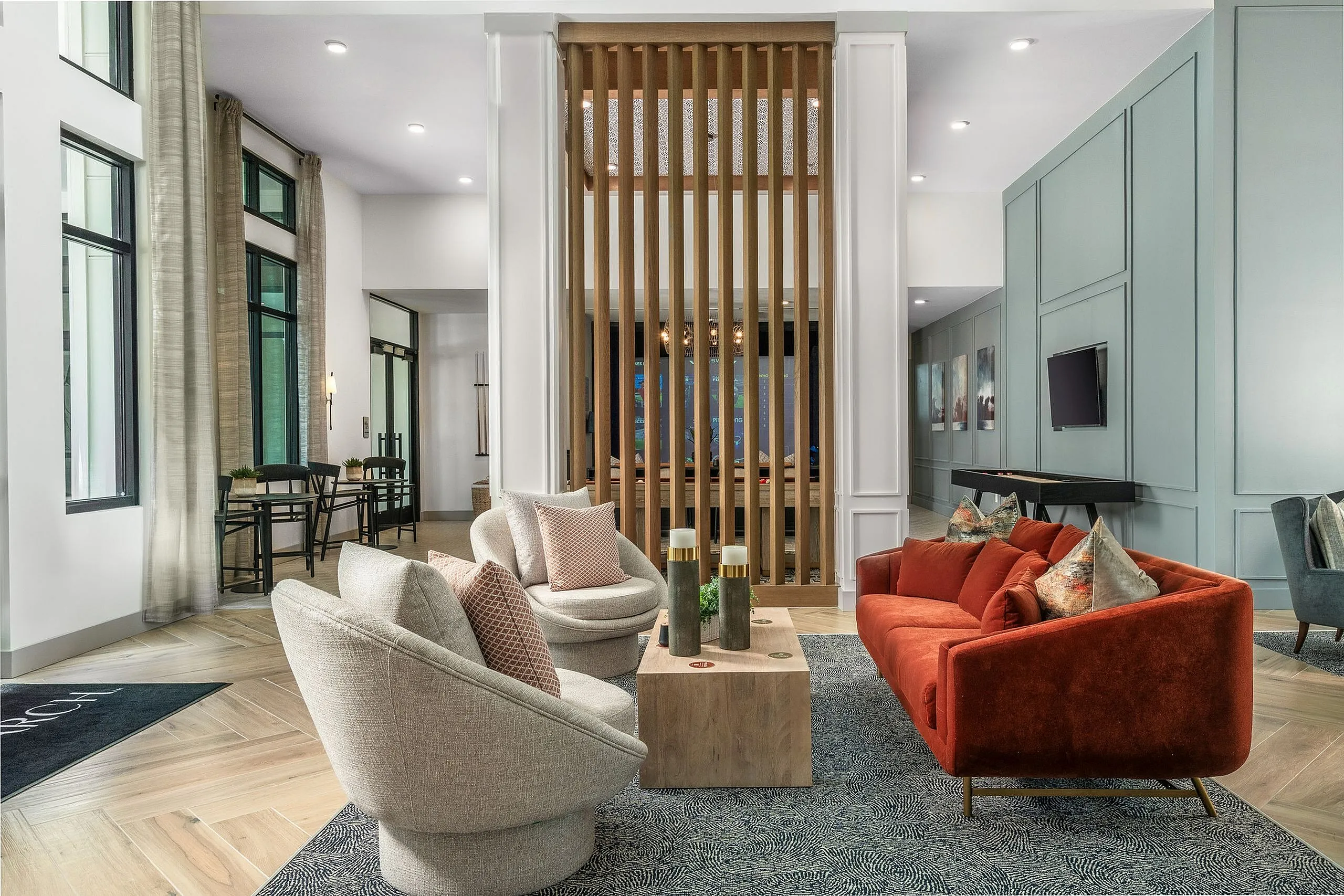 Contemporary open-plan living room featuring plush seating with elegant decor, a vibrant red sofa, and stylish accent chairs against a backdrop of chic modern panels.