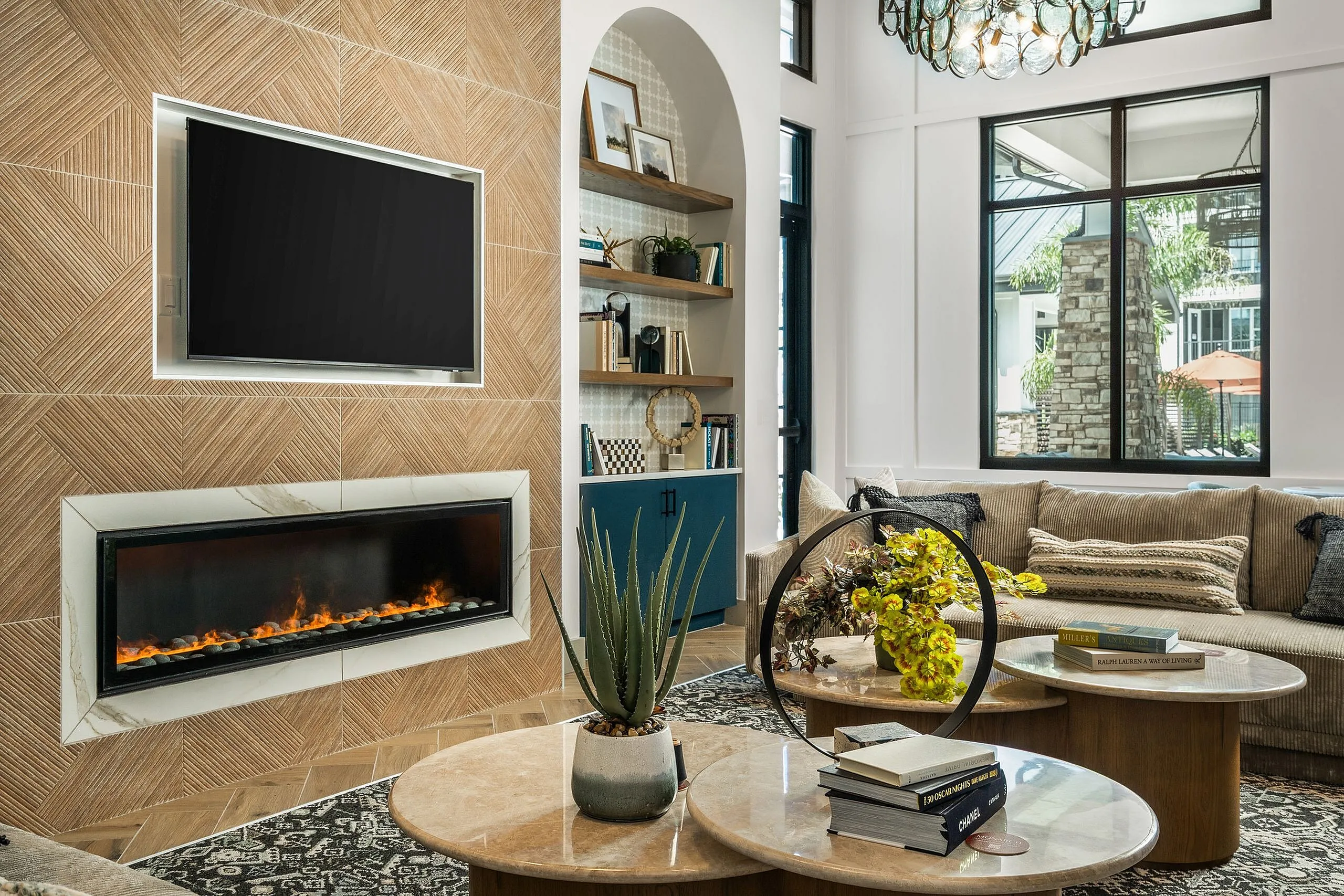 Luxurious living room showcasing a modern fireplace, elegant wall design, and cozy seating area, accented by stylish decor and large windows offering natural light.