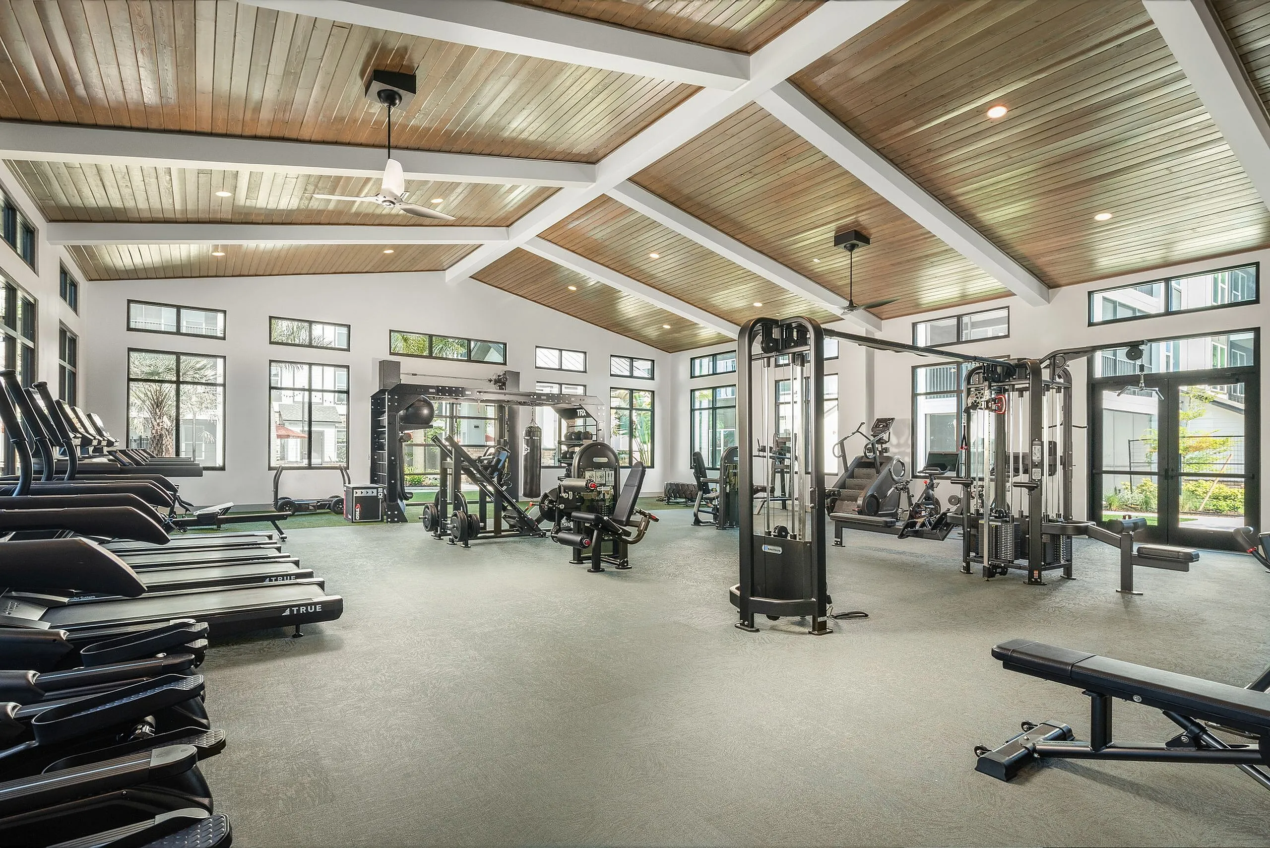 Spacious modern fitness center with high ceilings, large windows, and an array of state-of-the-art exercise equipment.