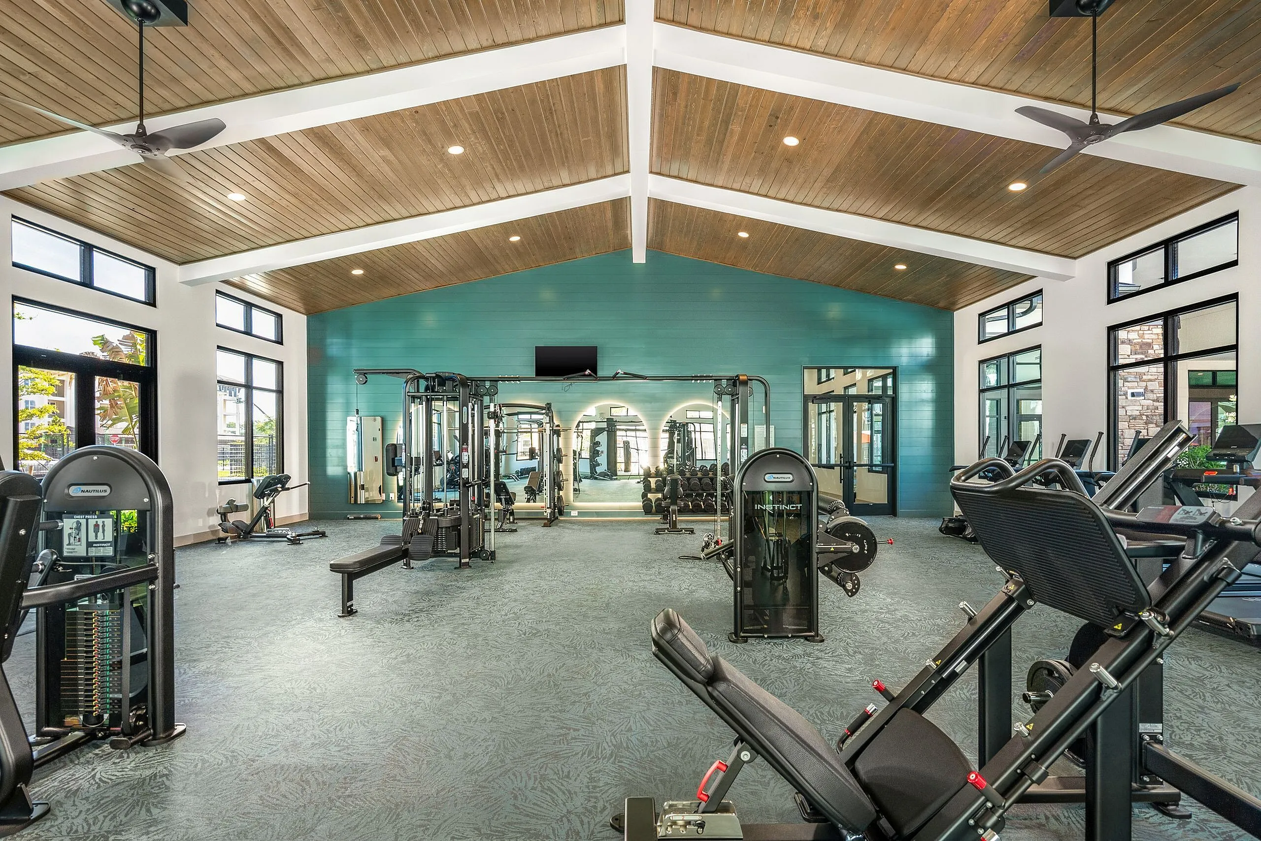Spacious, modern fitness center with high ceilings, featuring state-of-the-art exercise equipment and large windows for natural light.