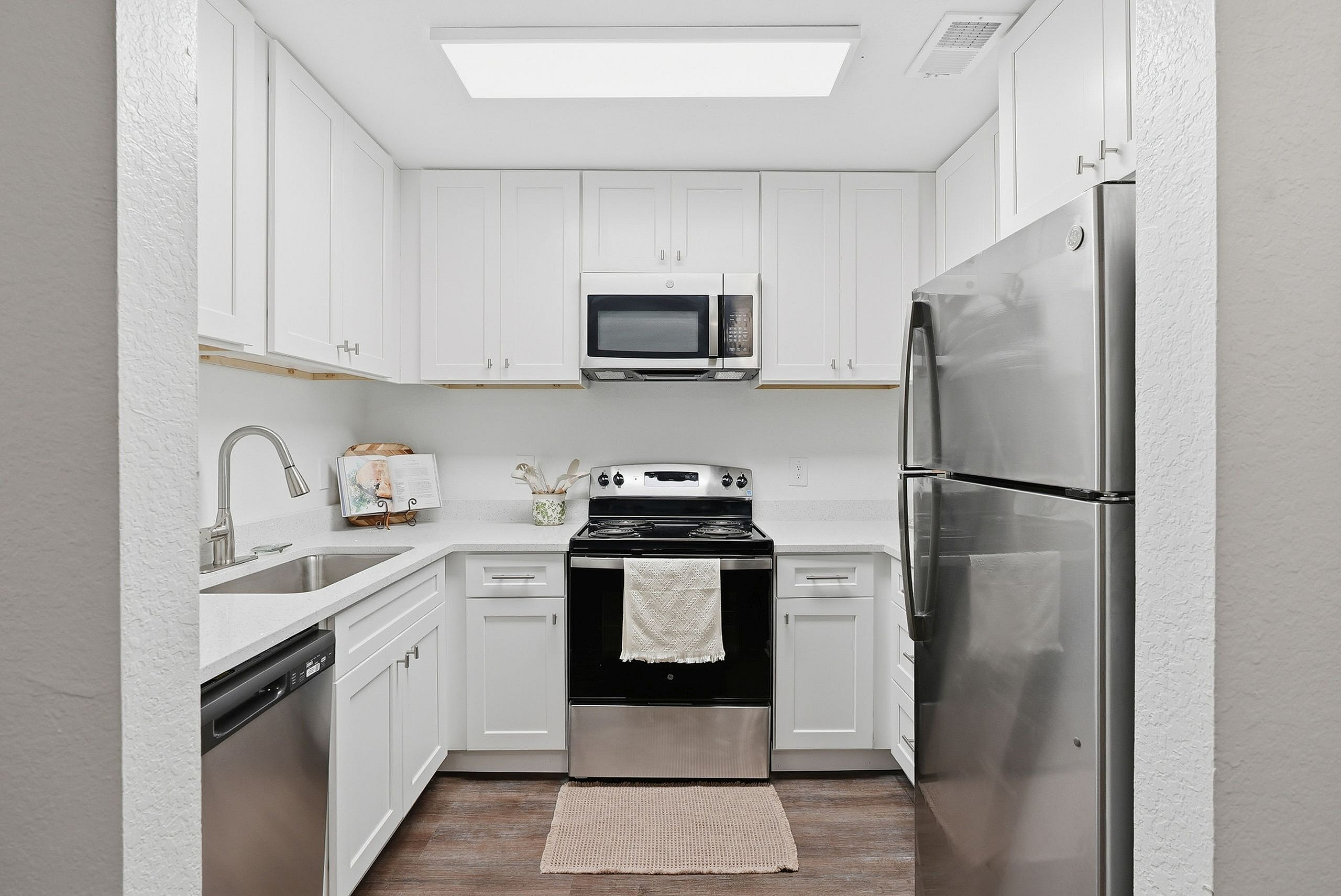 Bright and modern kitchen with sleek stainless steel appliances, pristine white cabinetry, and elegant countertops.