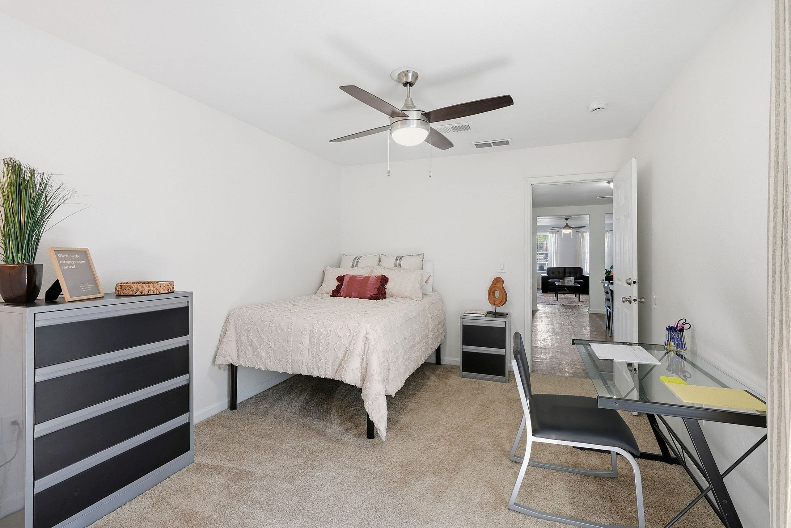 Charming bedroom with cozy decor, featuring a comfortable bed, modern ceiling fan, and sleek workspace. Ideal for relaxation and productivity.
