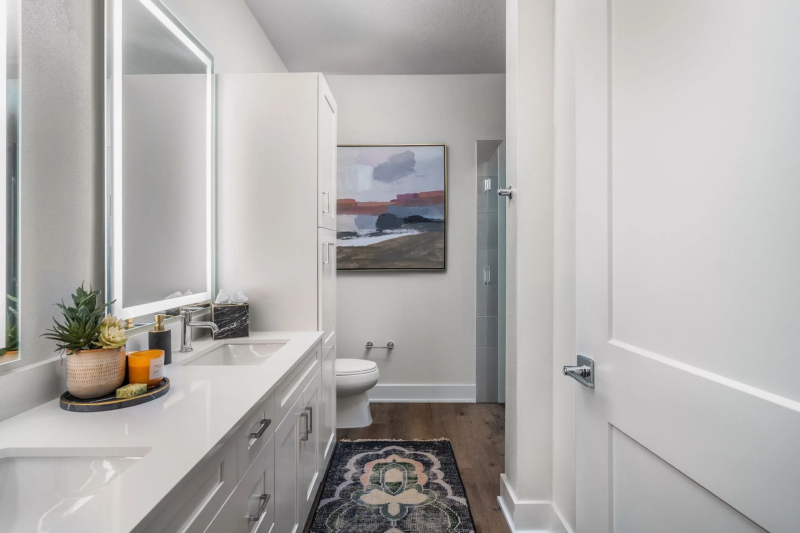 Elegant bathroom featuring a sleek vanity with twin sinks, modern fixtures, and decorative artwork for a sophisticated touch.