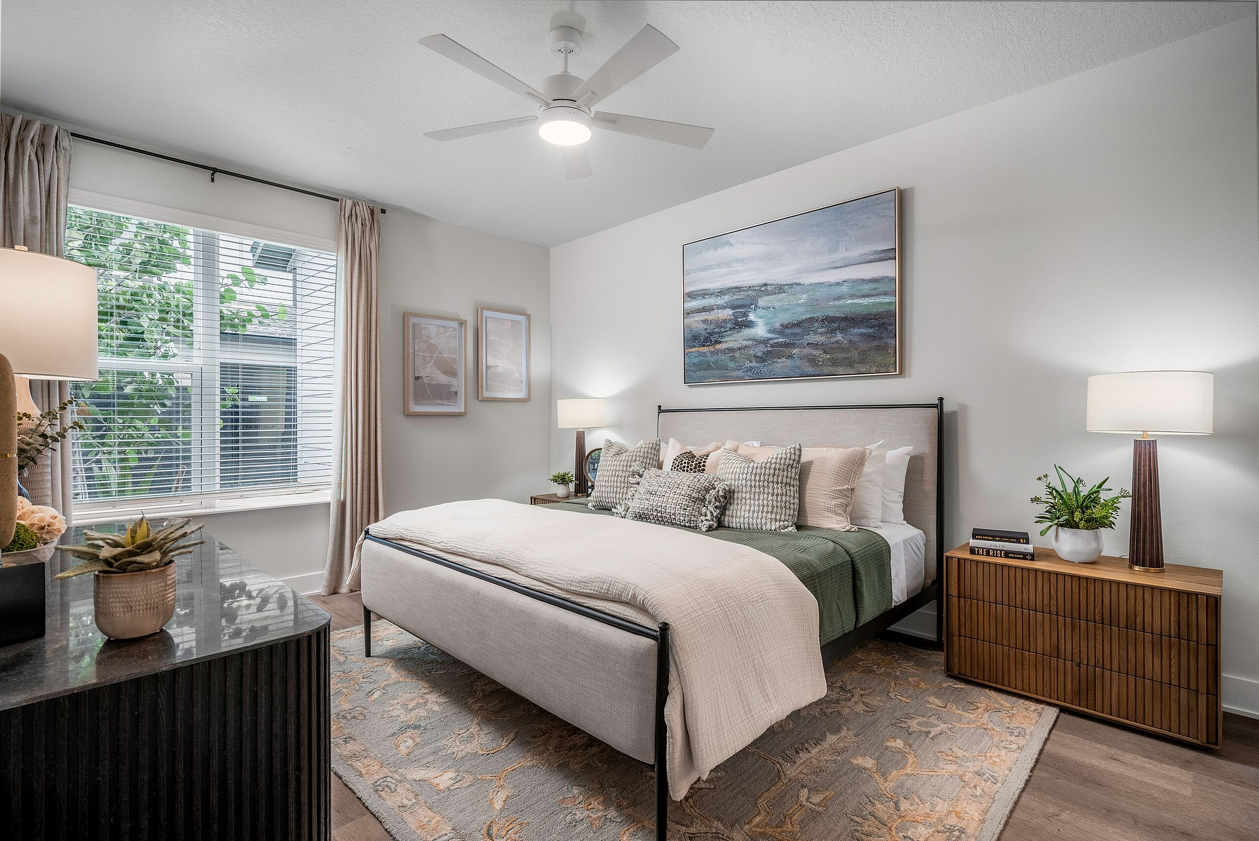 Elegant bedroom with modern decor, featuring a plush bed, stylish artwork, and abundant natural light through large windows.