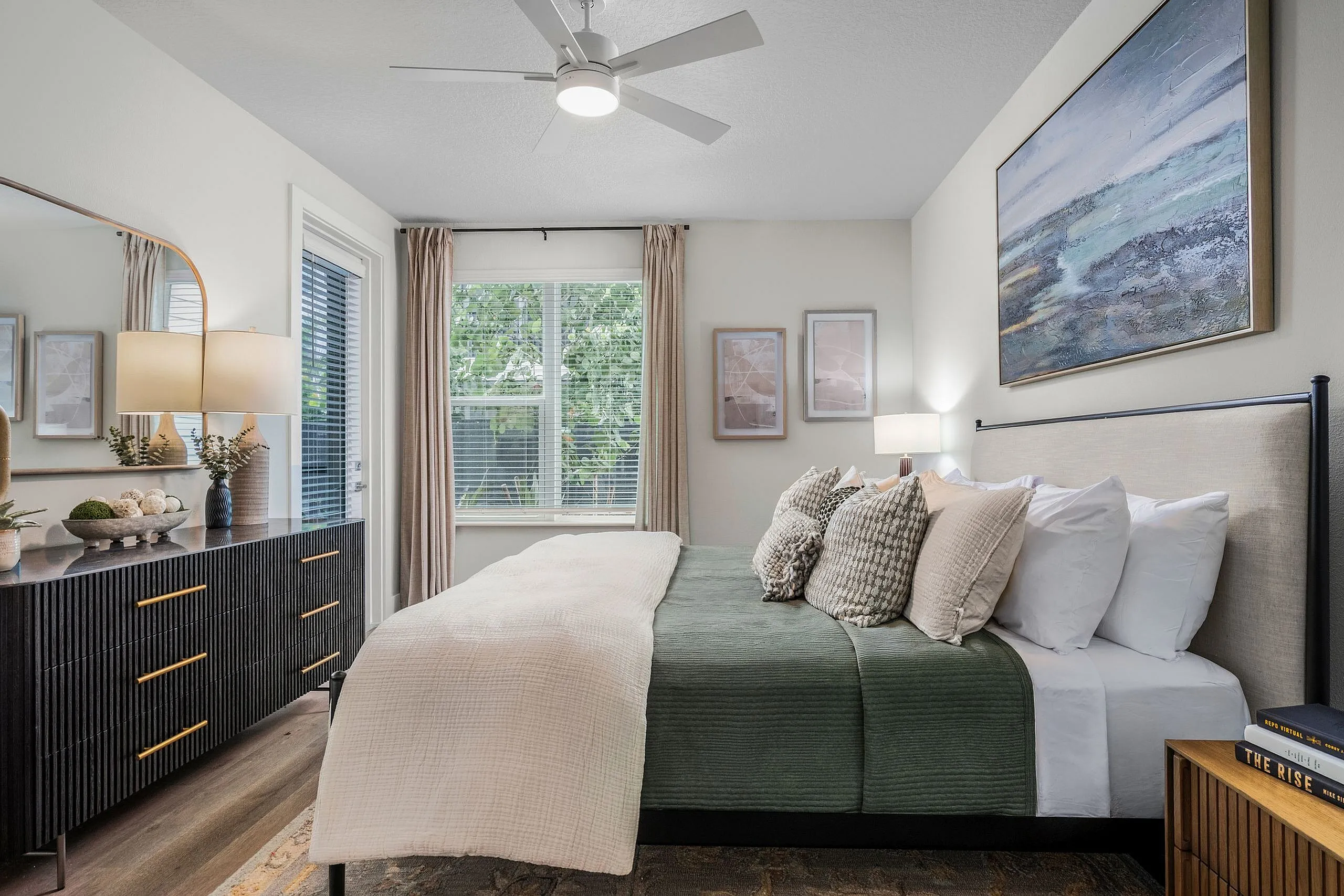 Elegant bedroom with stylish decor, featuring a cozy bed with plush pillows, modern dresser, and bright natural light through large windows.