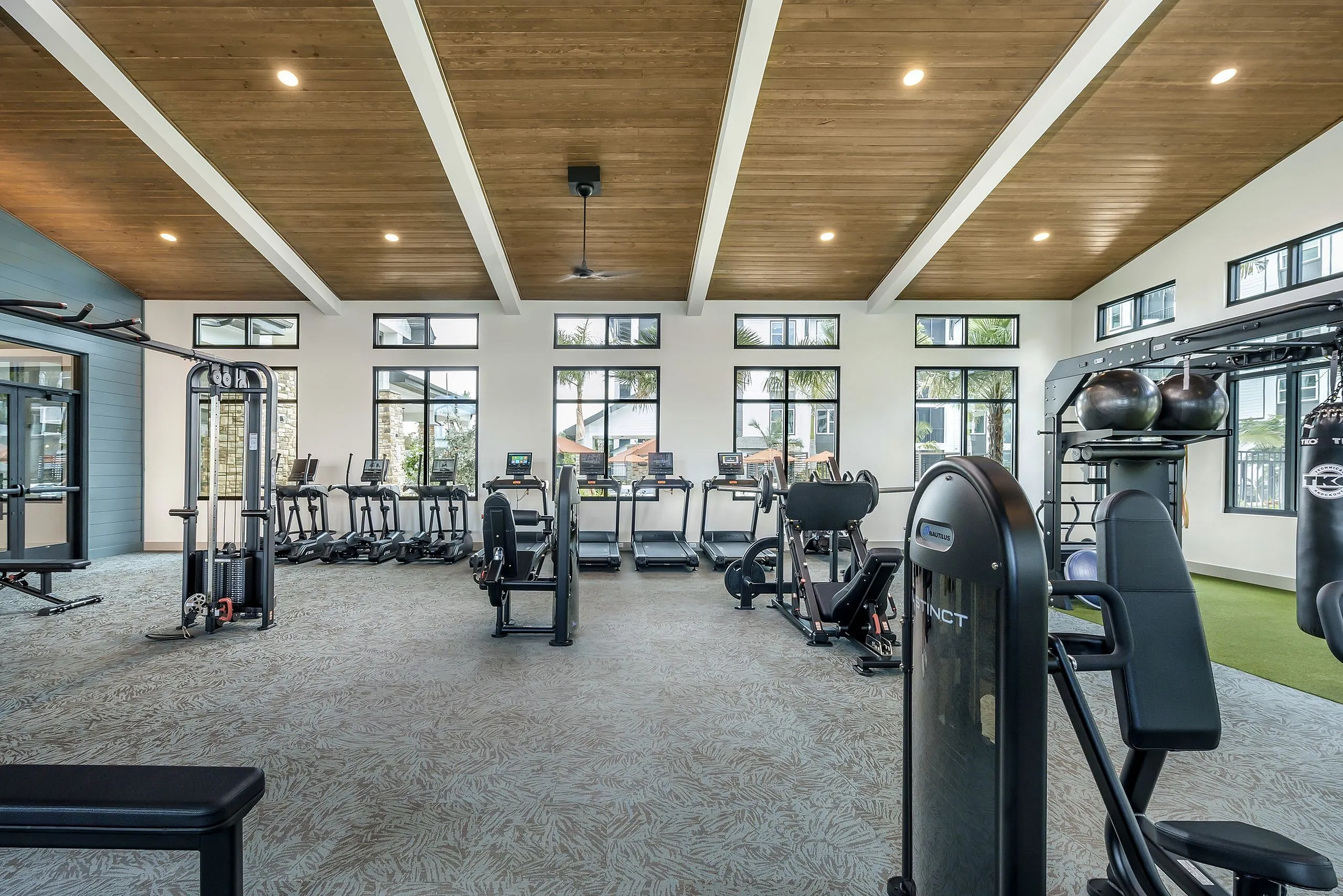 Modern fitness center with state-of-the-art equipment, treadmills, and weight machines, bathed in natural light from large windows.
