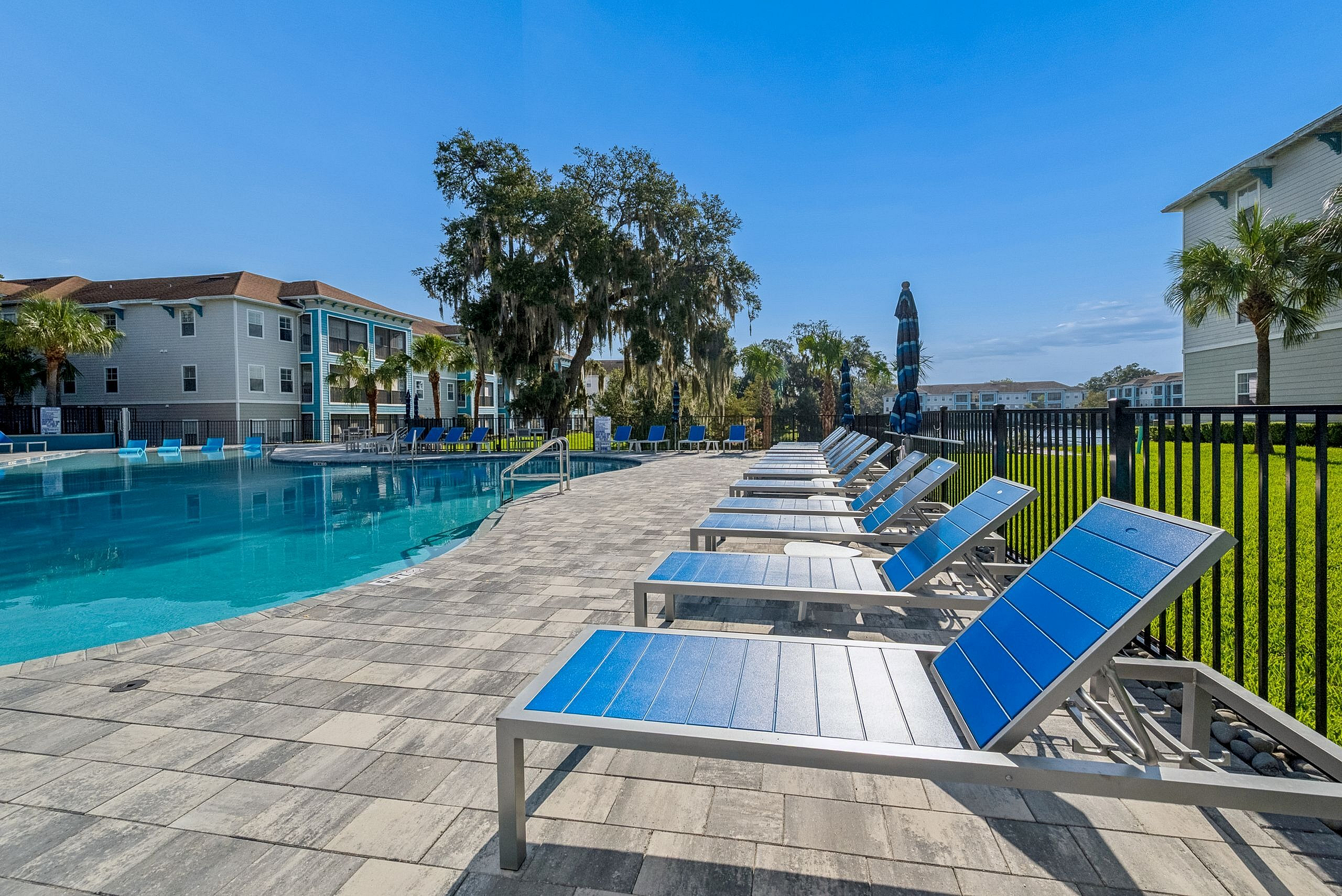 Inviting outdoor pool area with modern lounge chairs and lush greenery, perfect for relaxation and leisure.