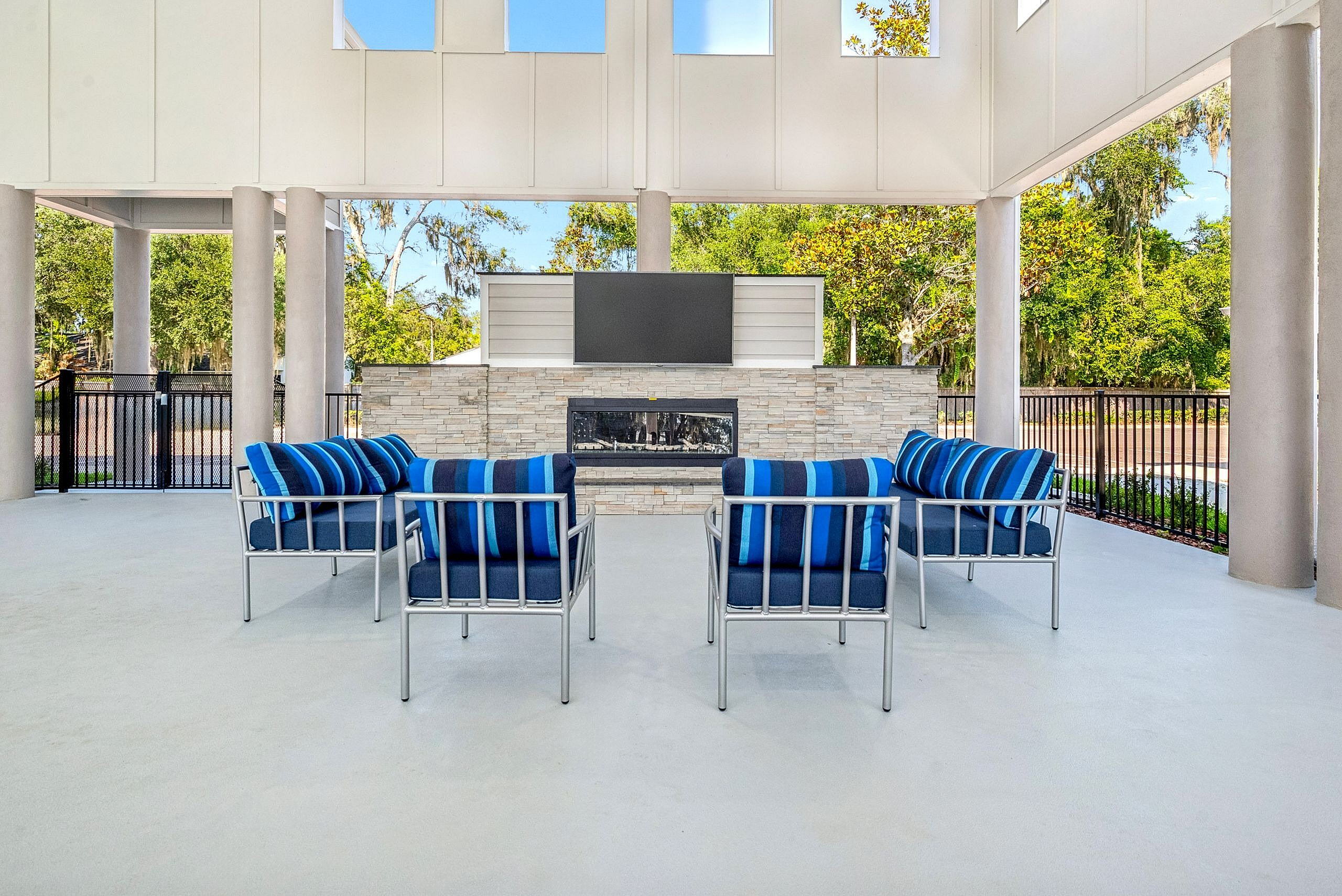 Charming outdoor seating area with modern blue-cushioned chairs and a sleek stone fireplace, perfect for relaxation and outdoor entertainment.