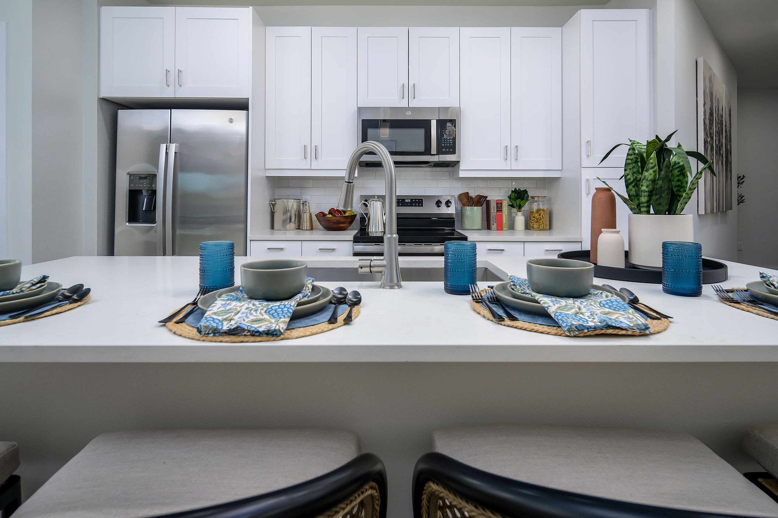 Chic modern kitchen with elegant white cabinetry, stainless steel appliances, and a stylish island set for dining.
