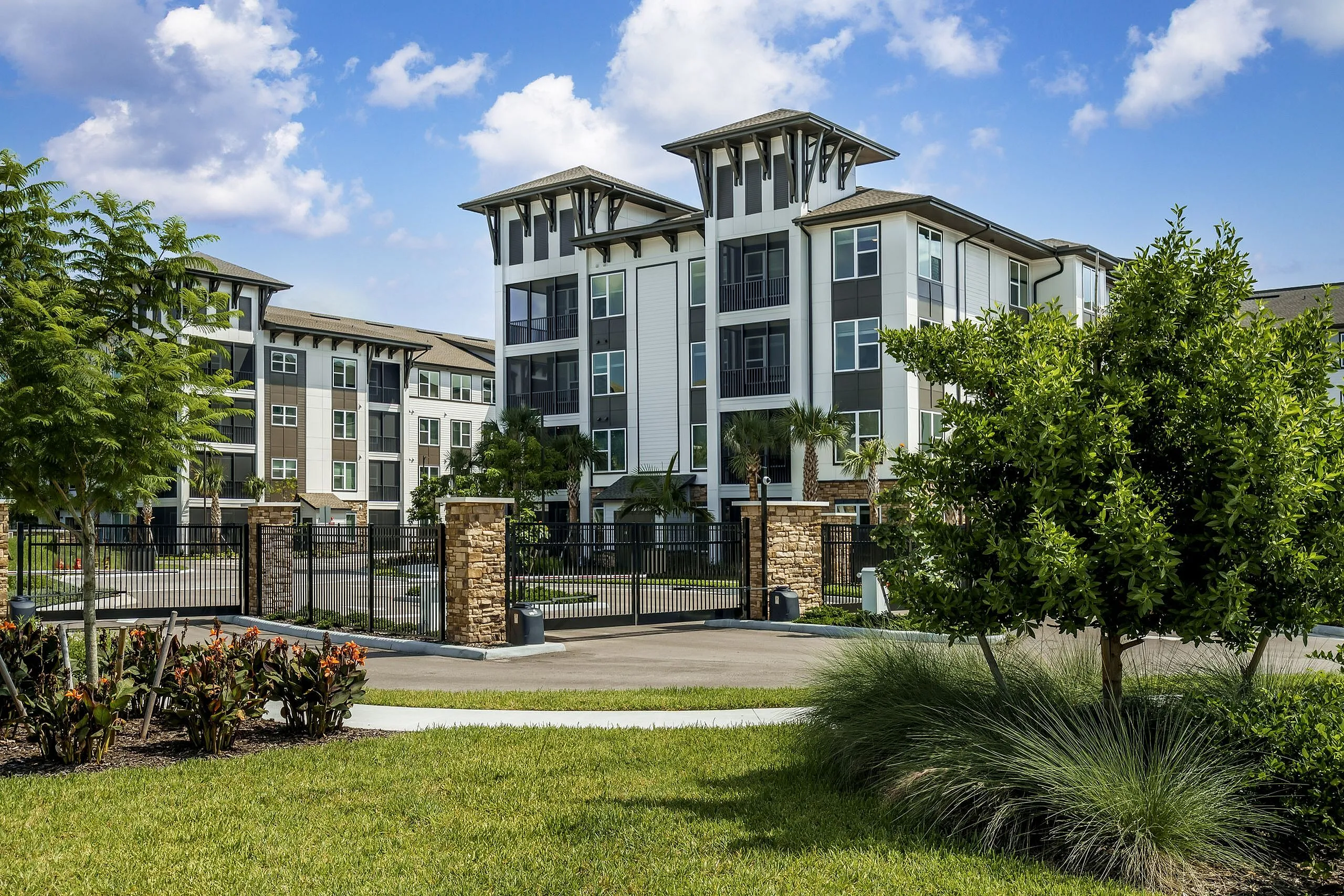 Elegant apartment complex featuring modern architecture with lush landscaping and a secure gated entrance.
