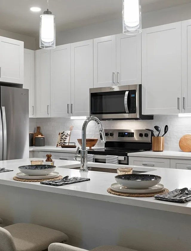 Elegant modern kitchen with sleek white cabinetry, stainless steel appliances, and a stylish breakfast bar set for dining.