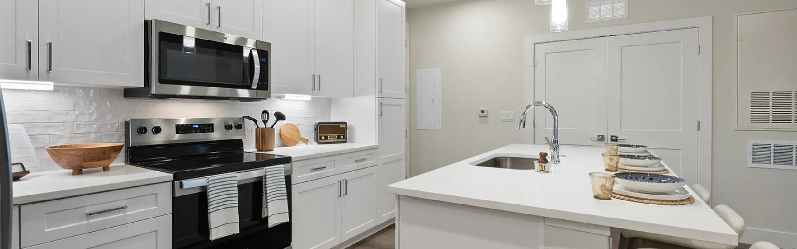 Contemporary kitchen with sleek white cabinets, modern stainless steel appliances, and a stylish island with seating.