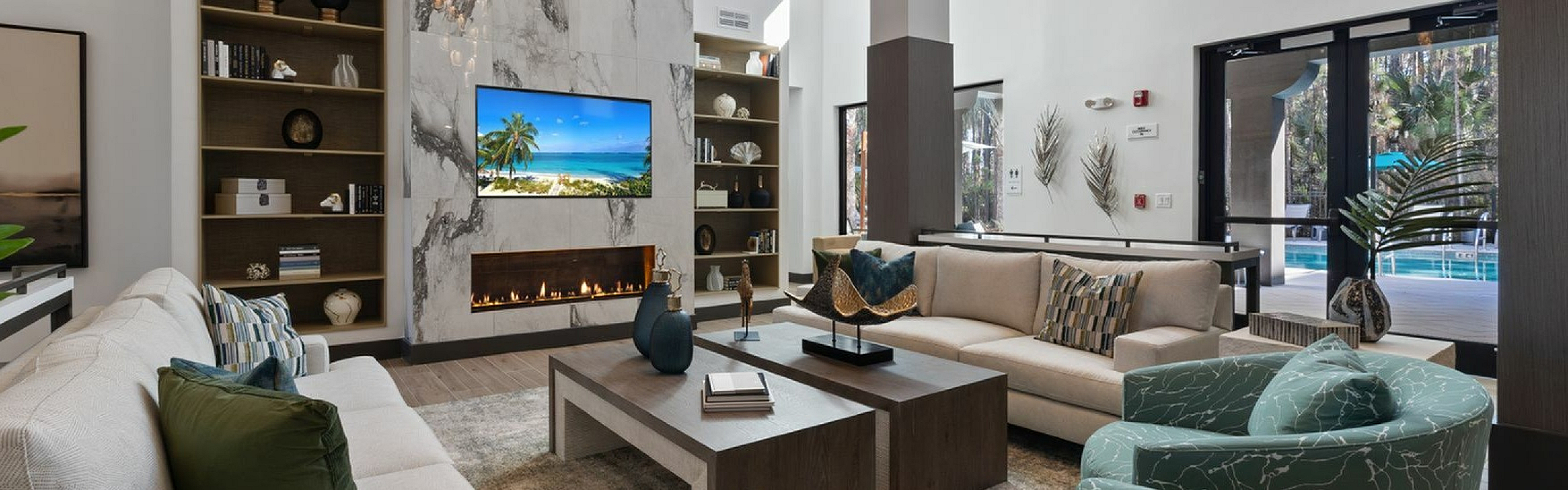 Elegant modern living area with stylish furniture, marble accent wall, and large windows overlooking the pool area.