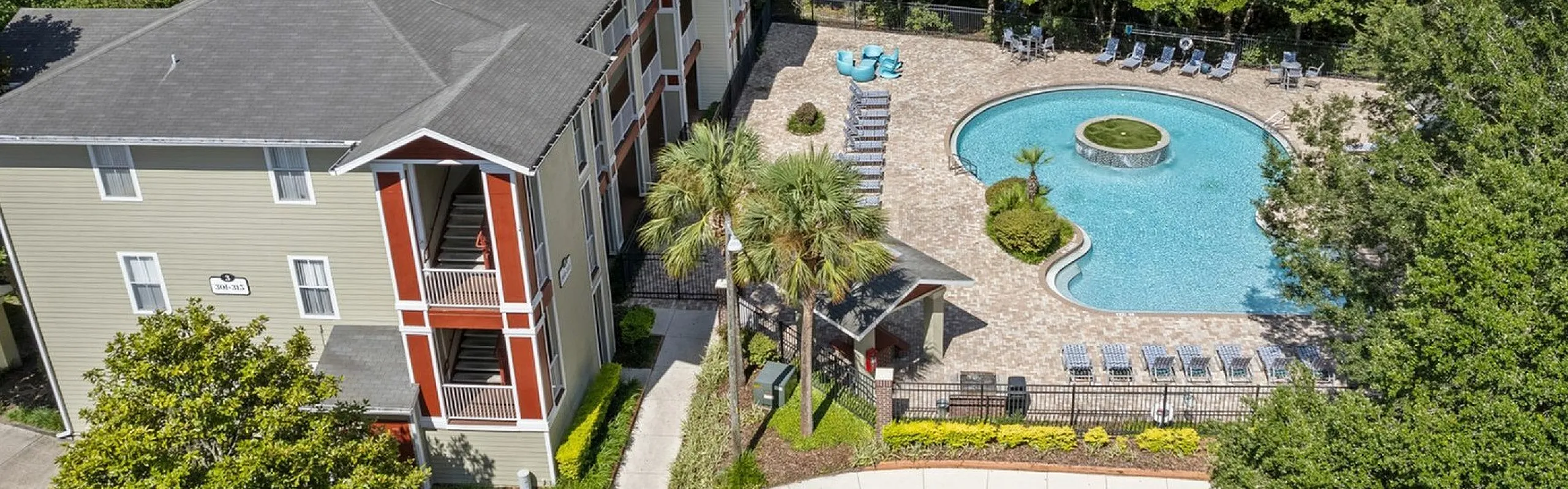 Lush apartment complex featuring a scenic outdoor pool surrounded by greenery and comfortable lounging chairs, perfect for relaxation.